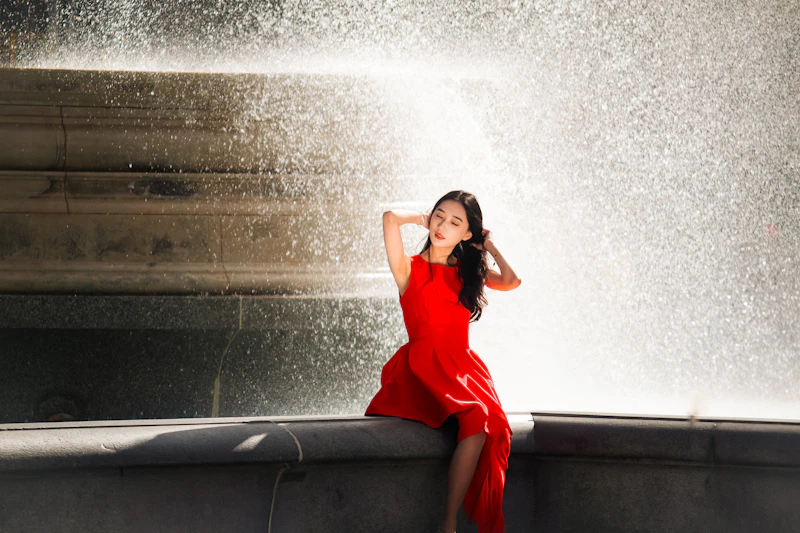 woman in red dress sitting by fountain