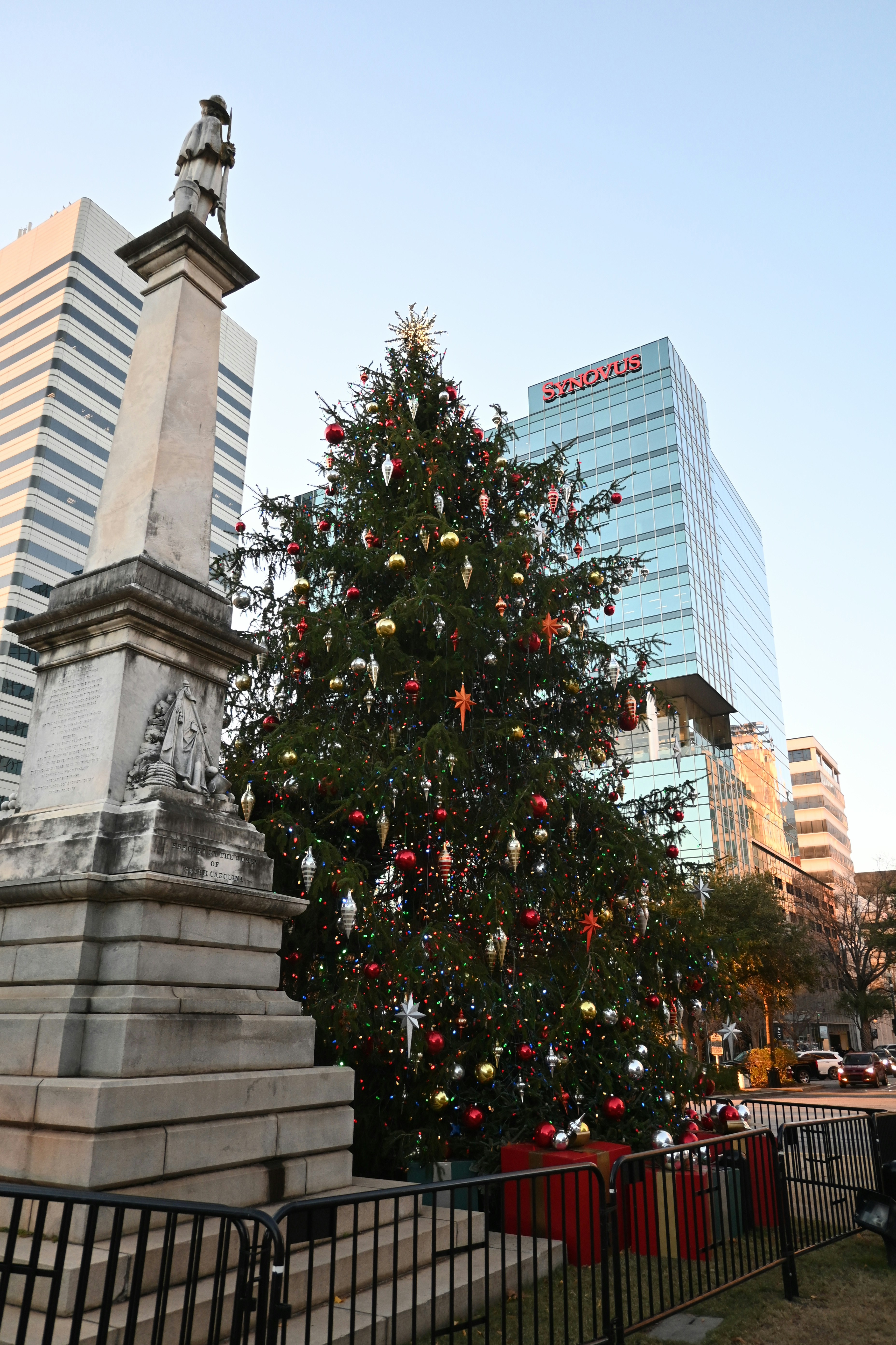 Geschmückter Weihnachtsbaum mit Denkmal und modernen Gebäuden.