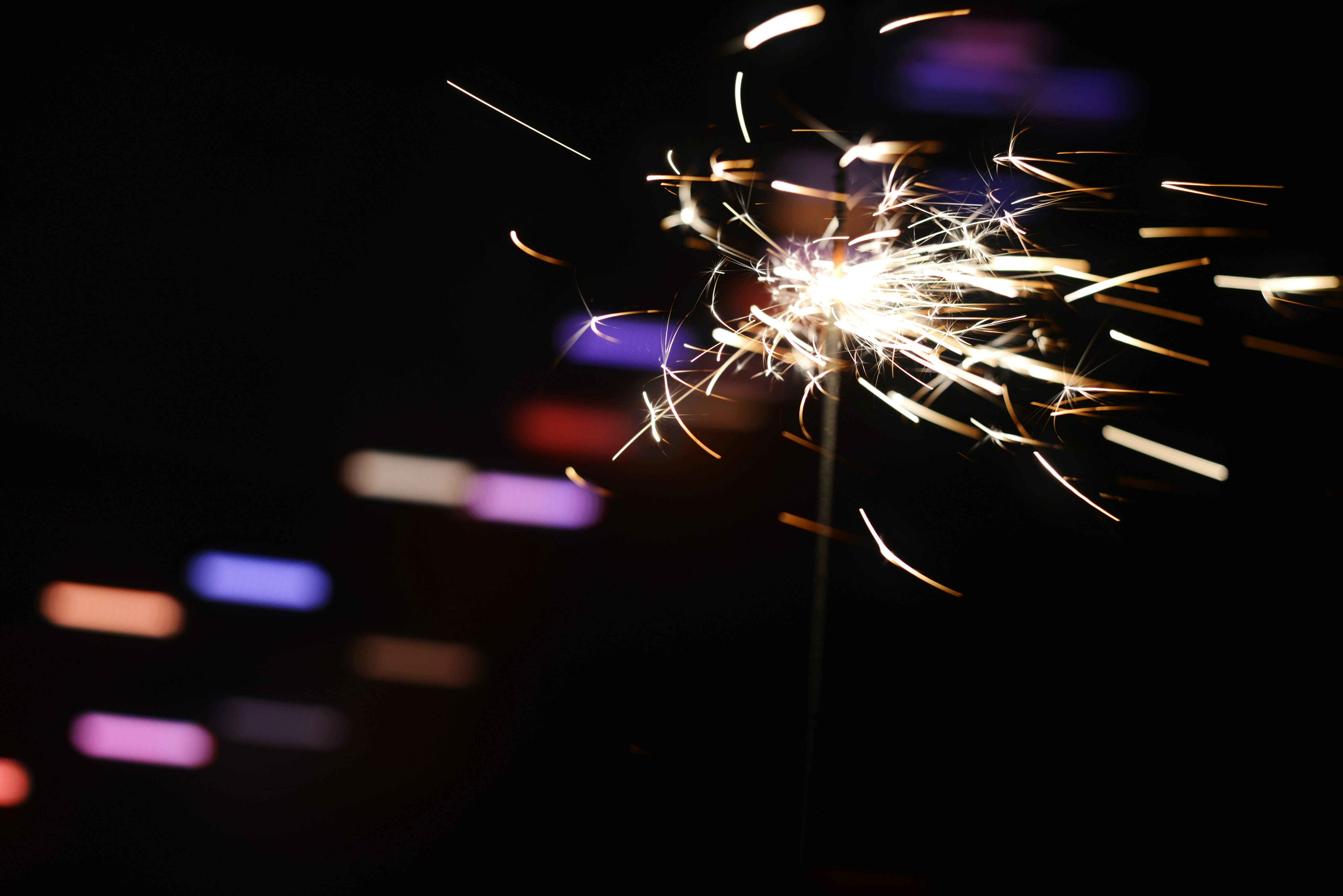 Sparkler ignites with bright sparks against dark background