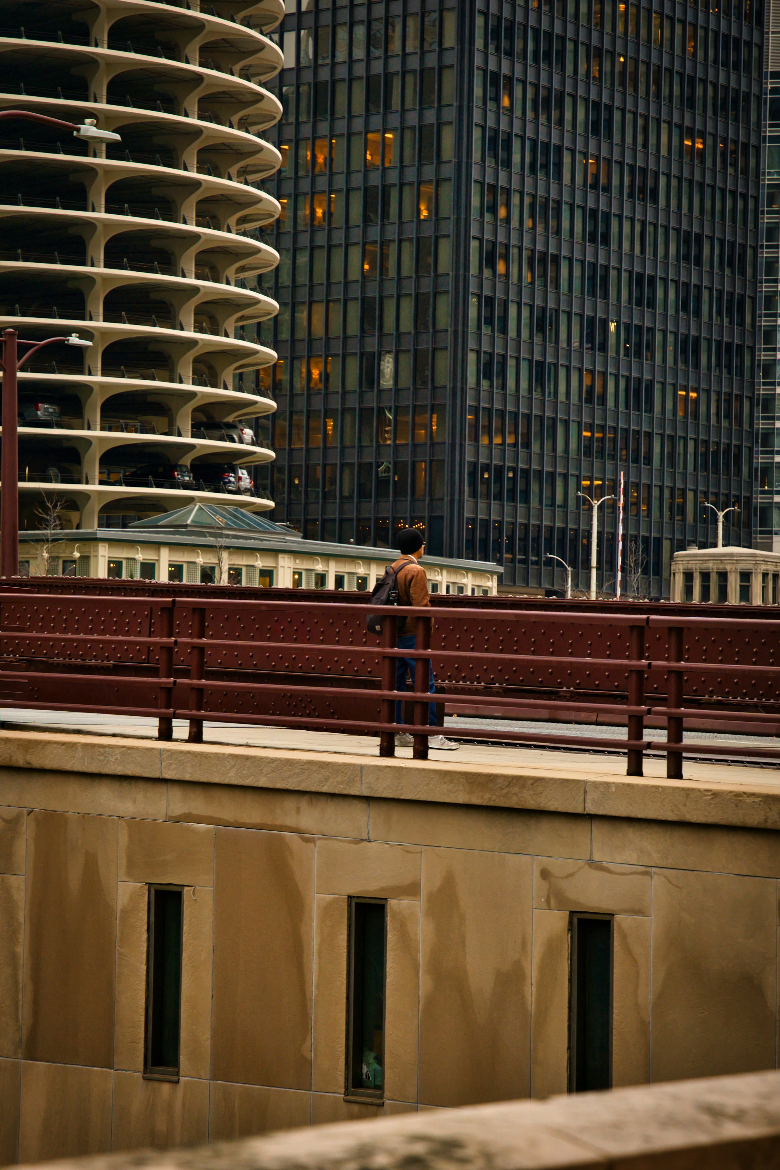 Person walks on bridge with modern buildings behind