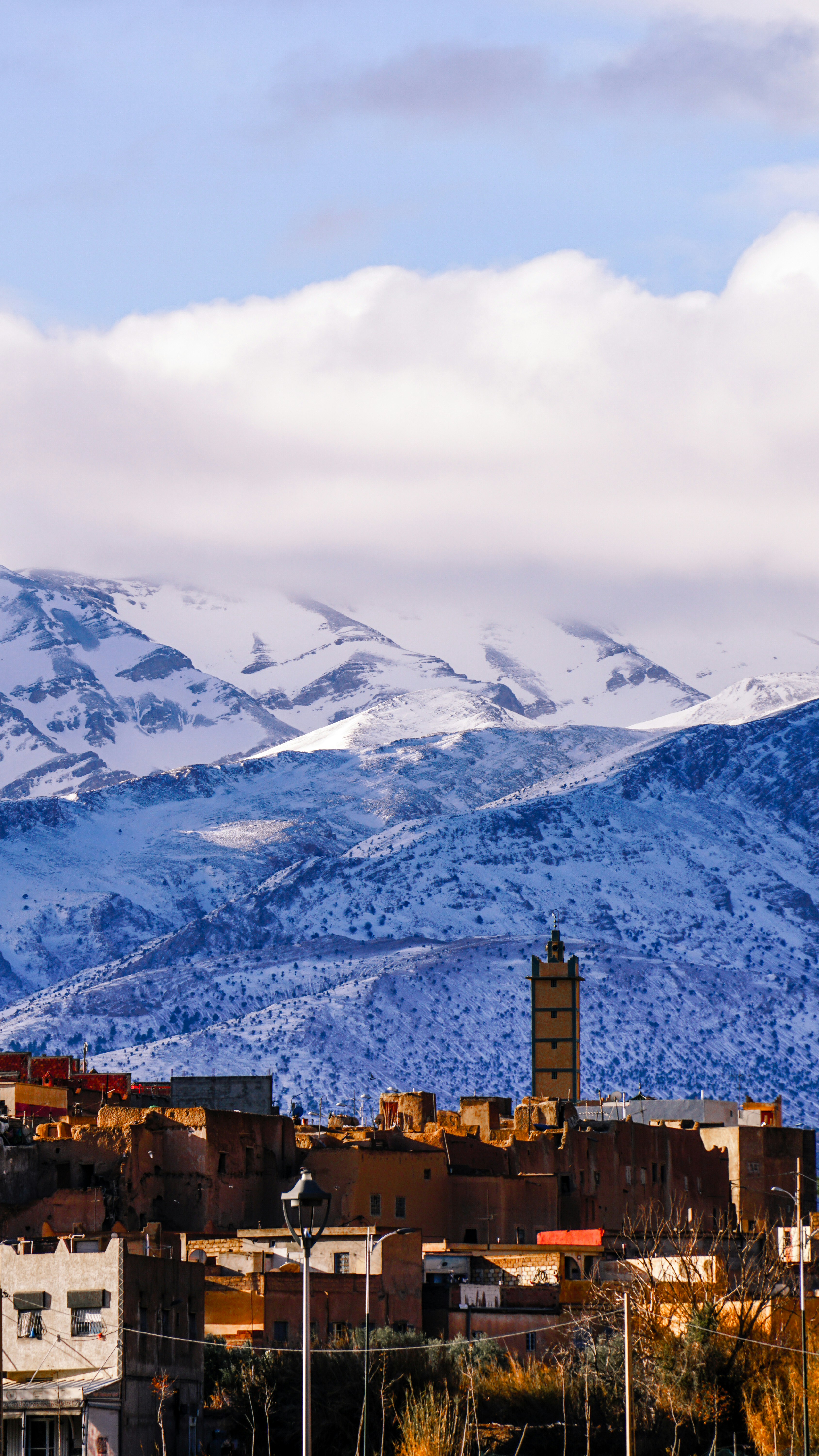Snowy mountains overlook a moroccan village with a minaret.