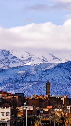 Snowy mountains overlook a moroccan village with a minaret.