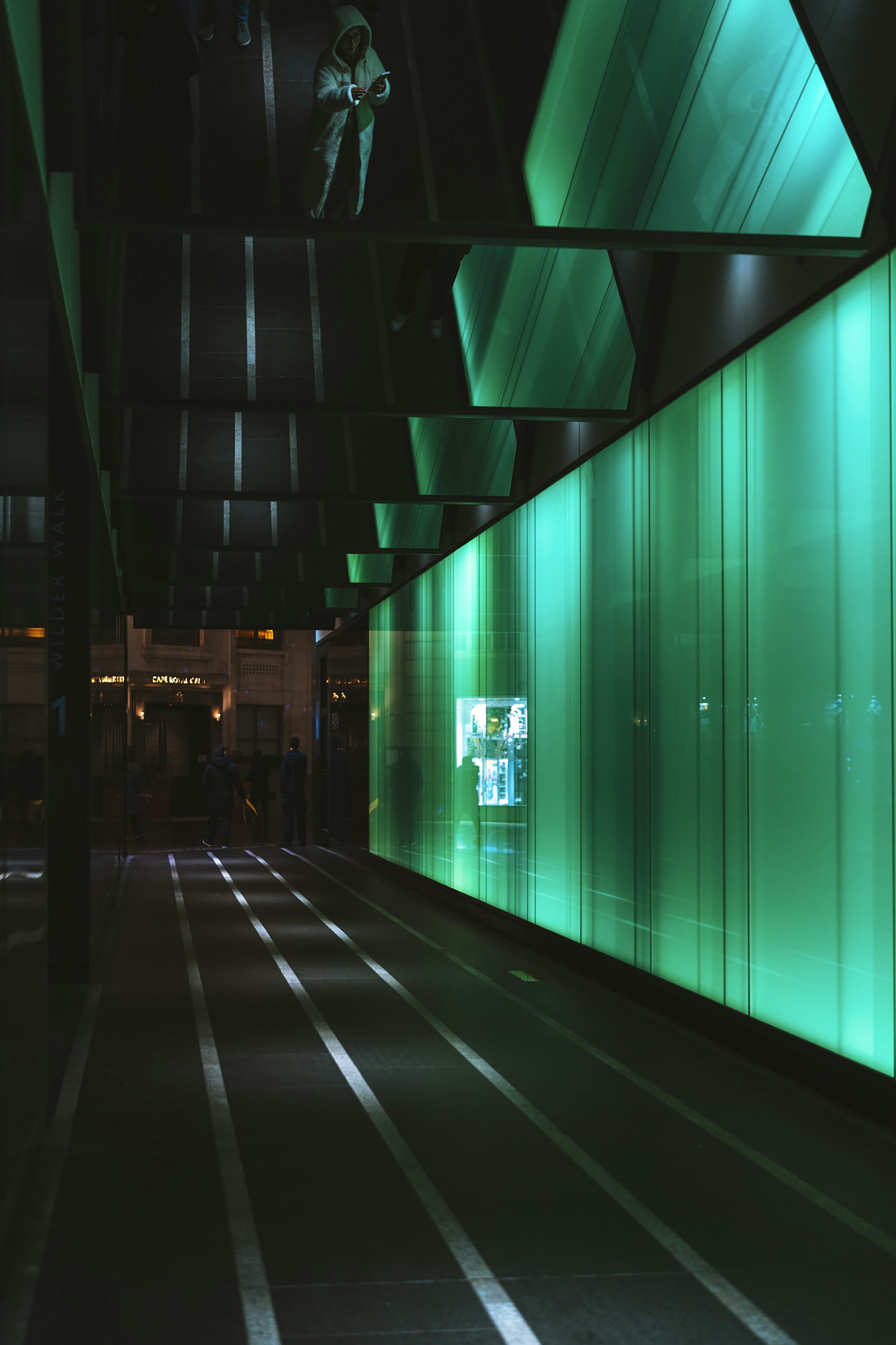 Modern hallway with glowing green wall and reflections