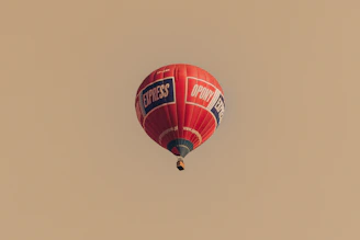 Red hot air balloon with logos flying in sky
