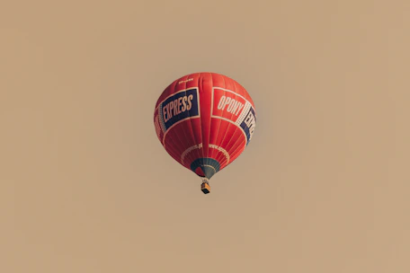 Red hot air balloon with logos flying in sky