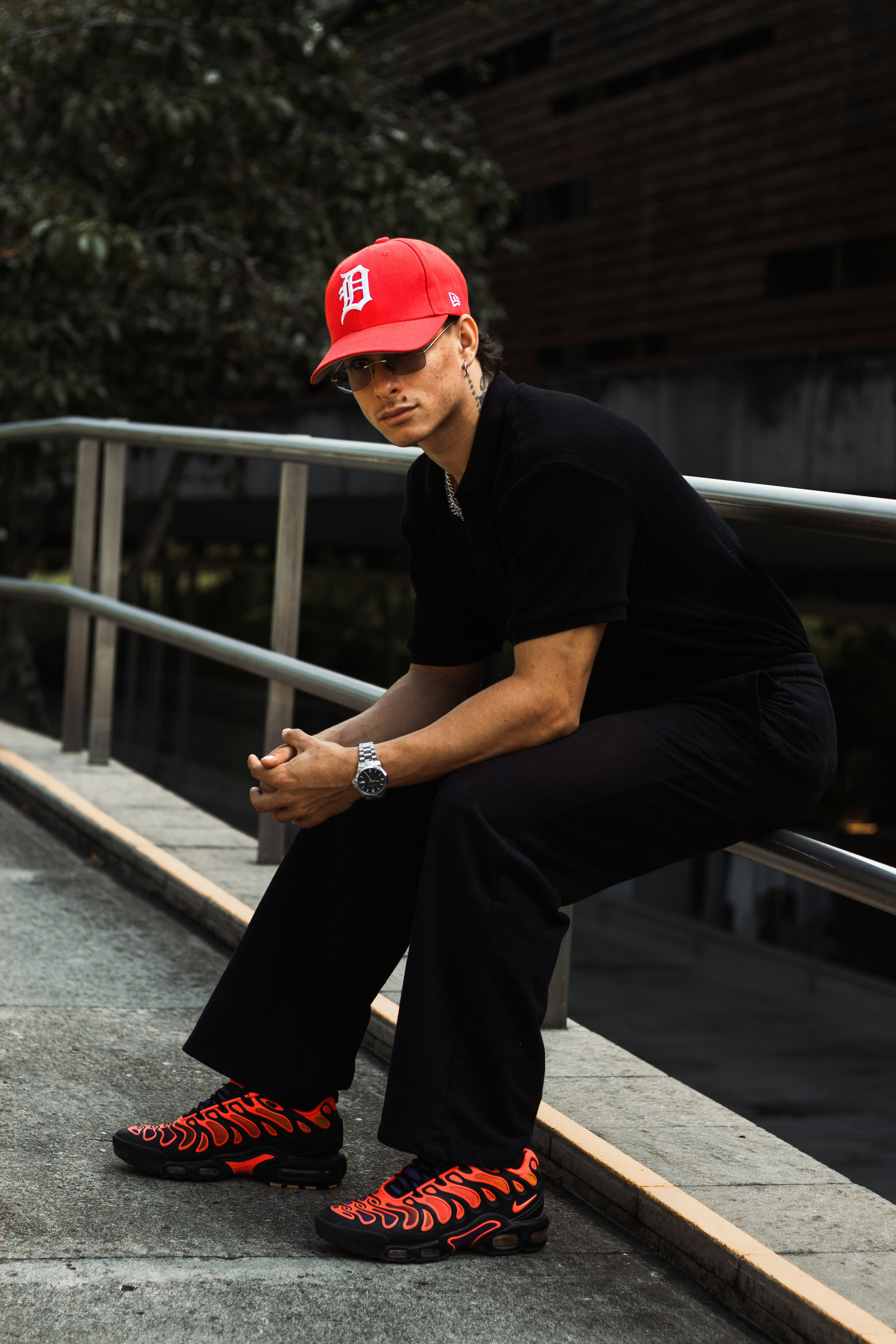 Man in red cap and black shirt sits outdoors.