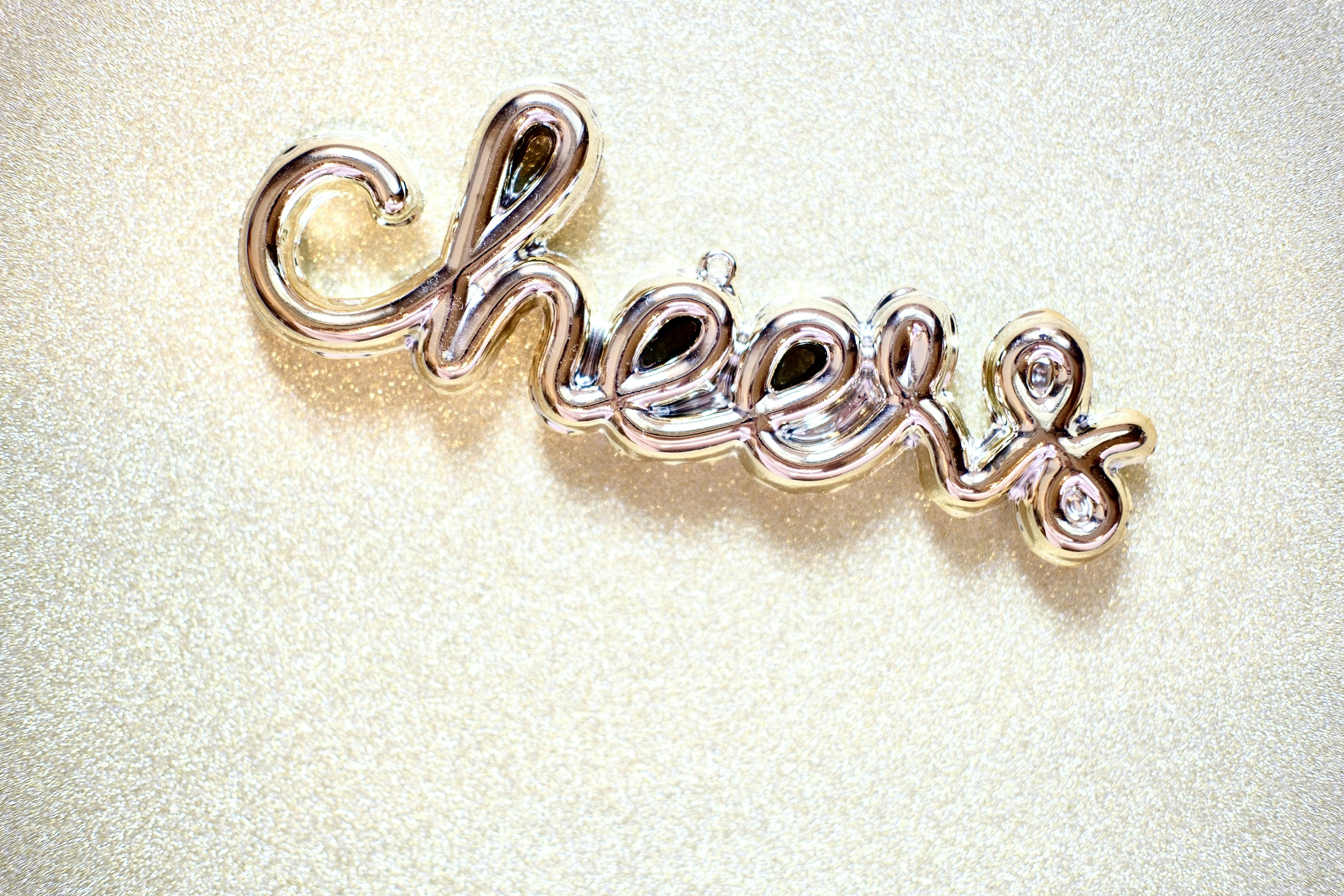 Silver cursive word 'cheers' with small diamonds.