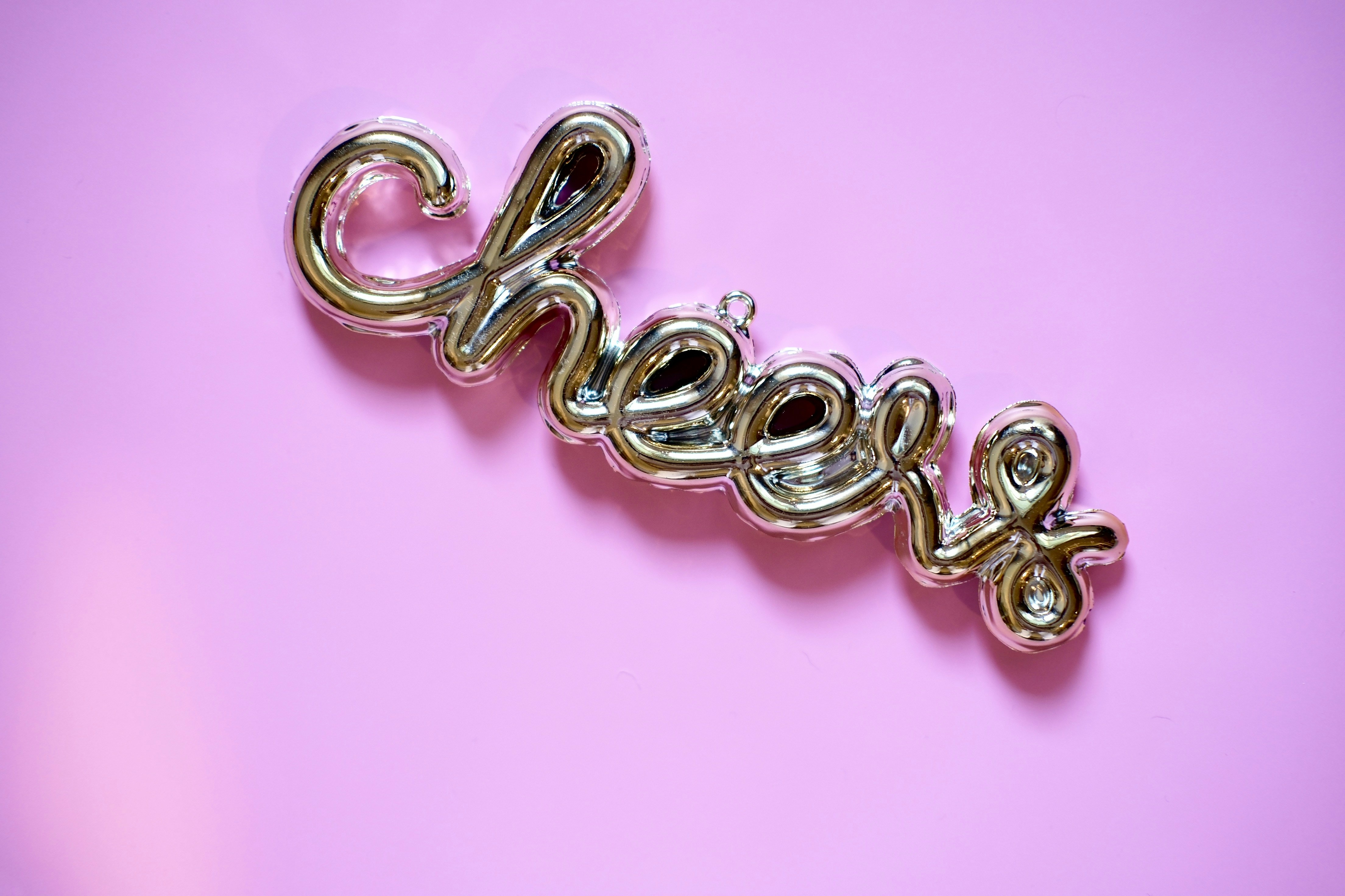 Silver "cheers" word decoration on pink background