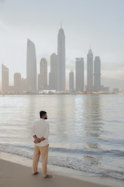 Man standing on beach overlooking city skyline
