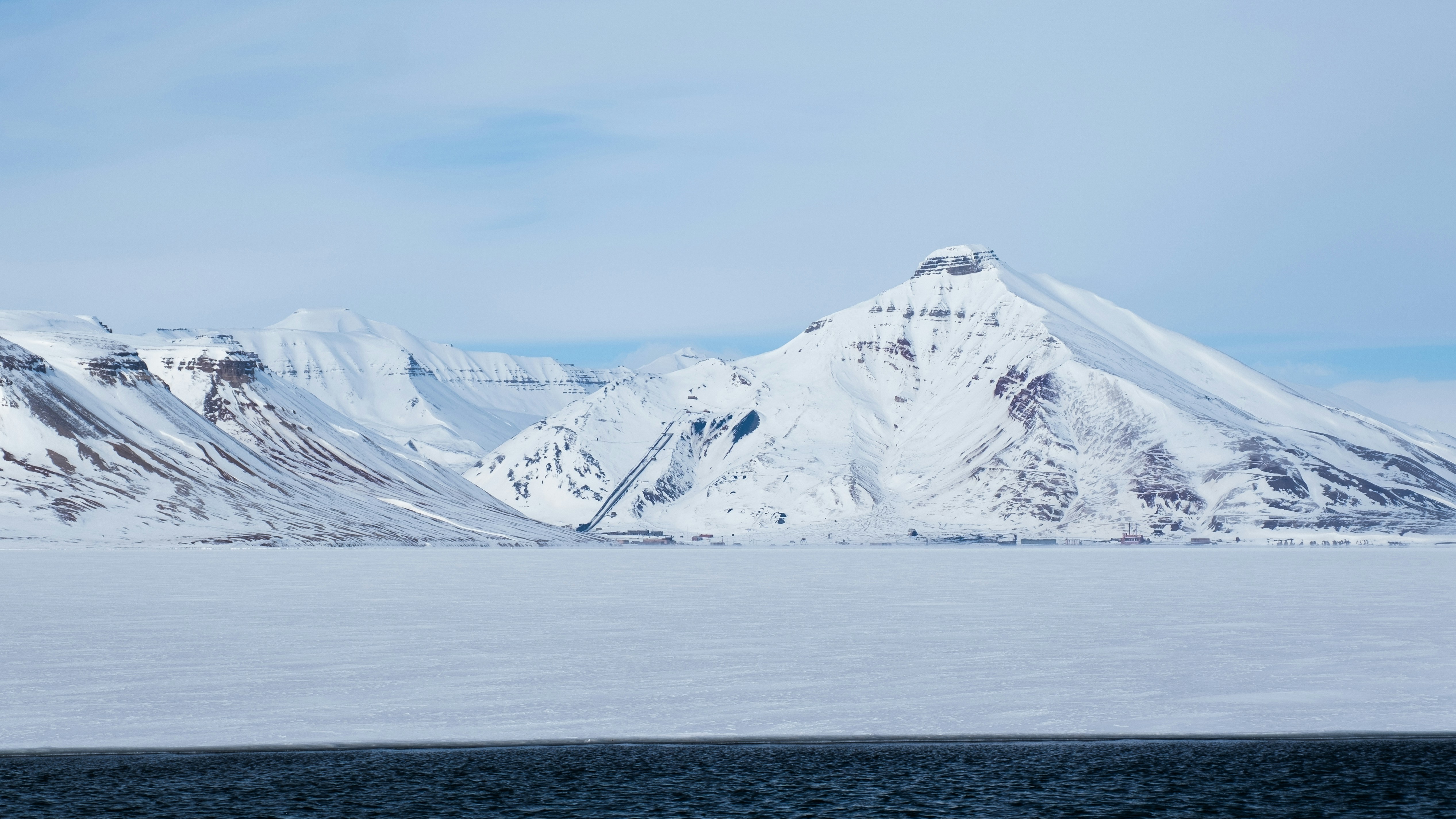 Snow-covered mountains rise above a frozen landscape.