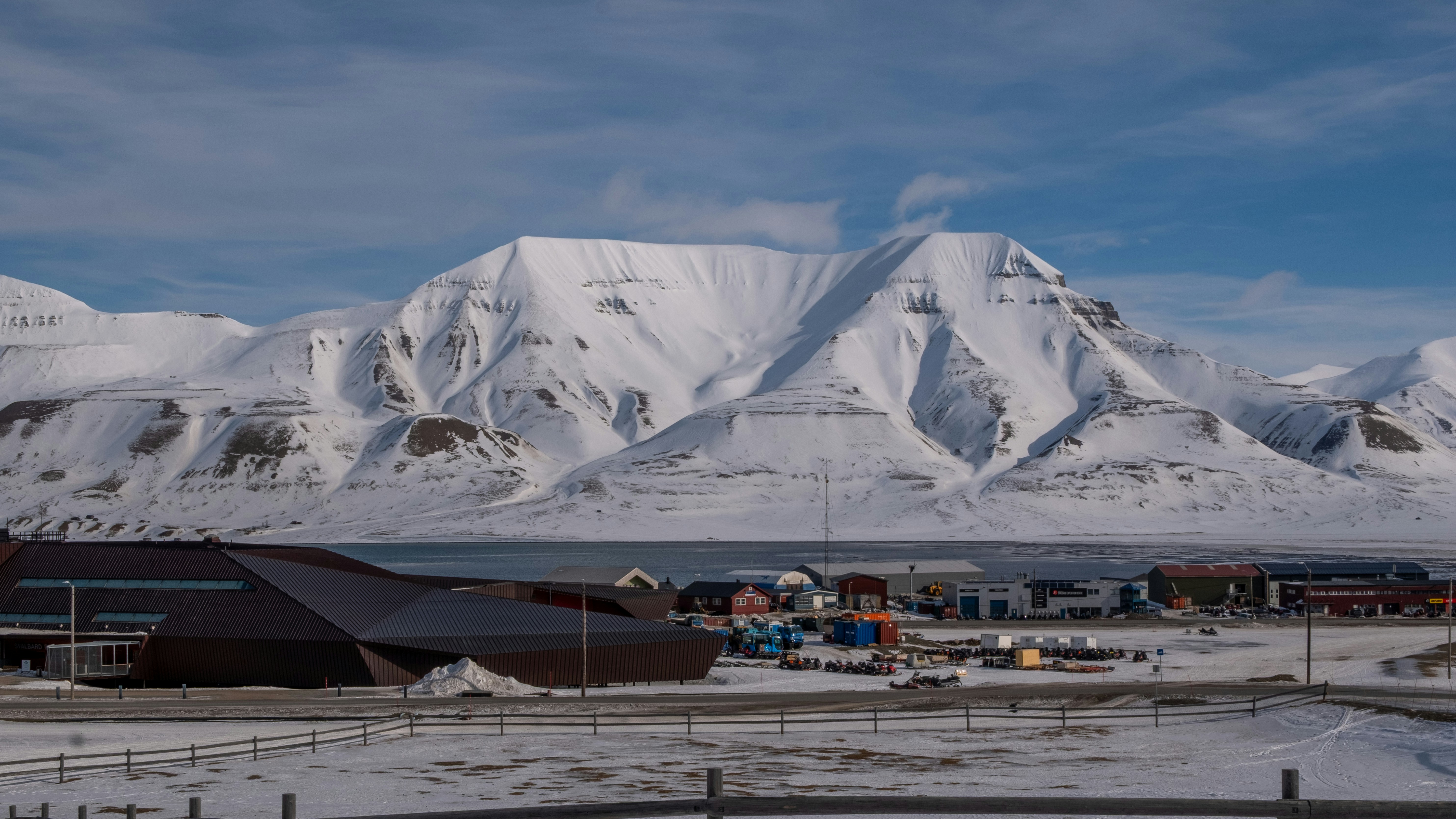 Snowy mountains overlook a small town by the sea.