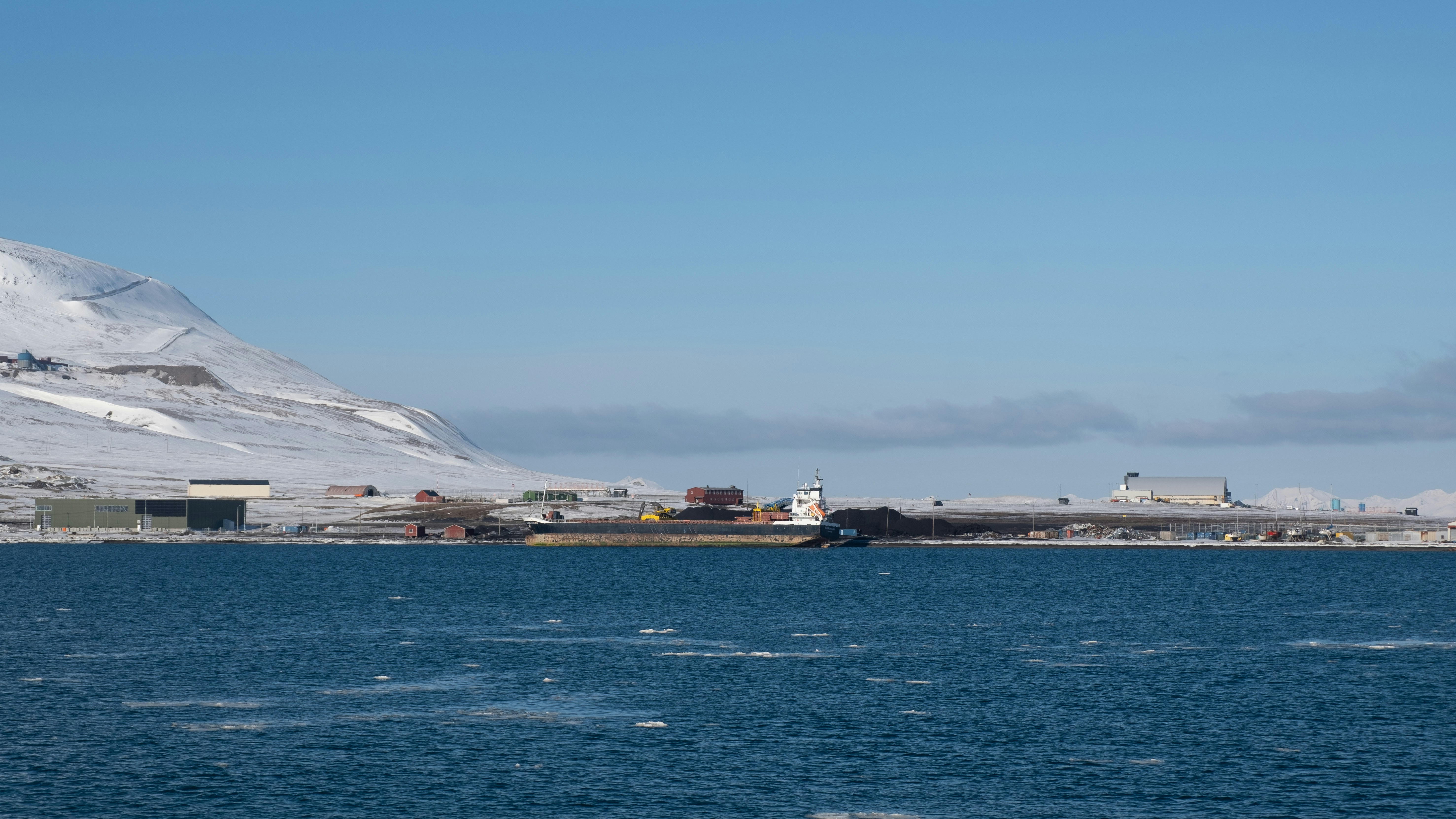 Coastal buildings on a snowy mountainside by the ocean.