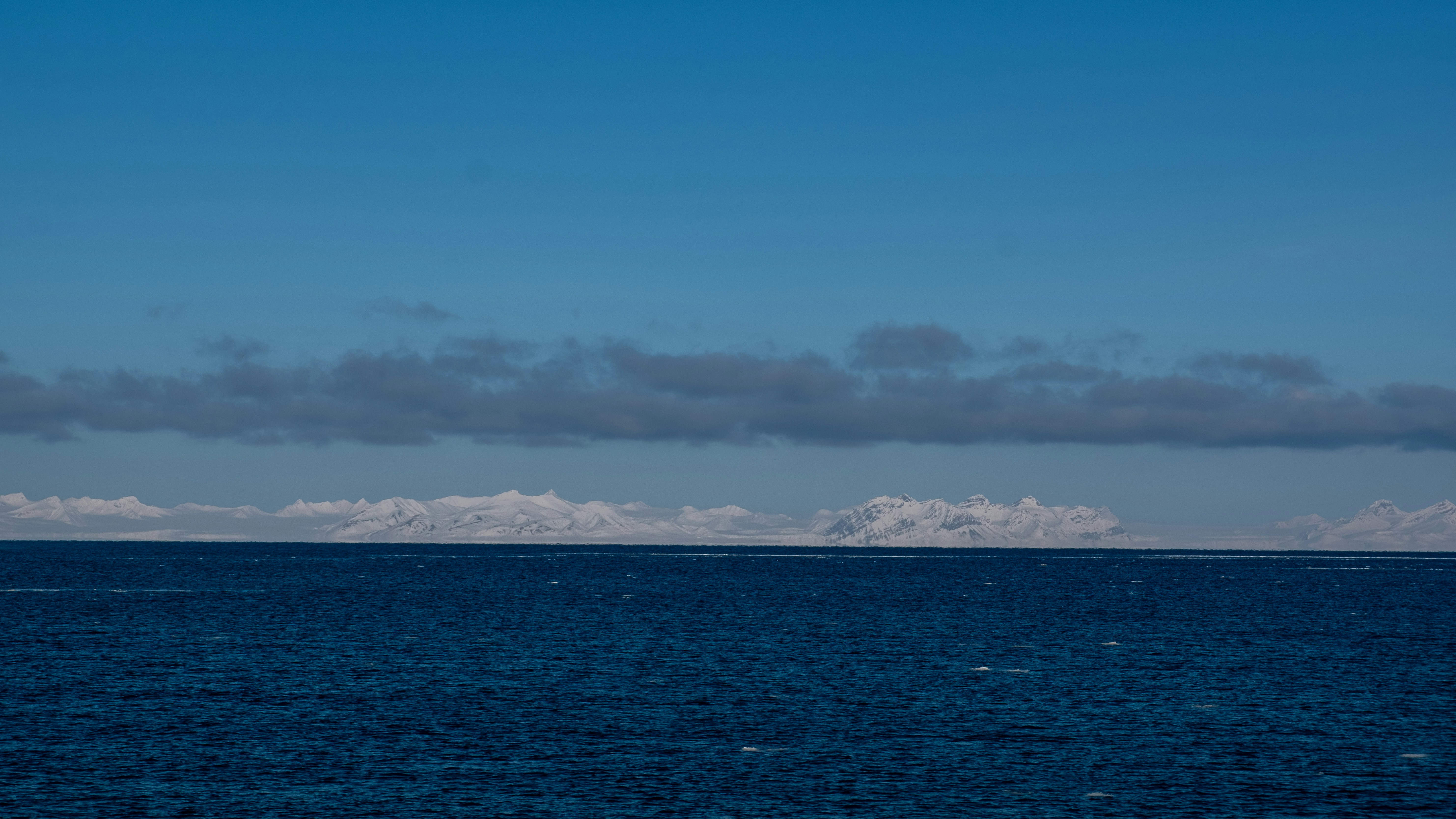 Deep blue ocean under a clear sky with clouds.
