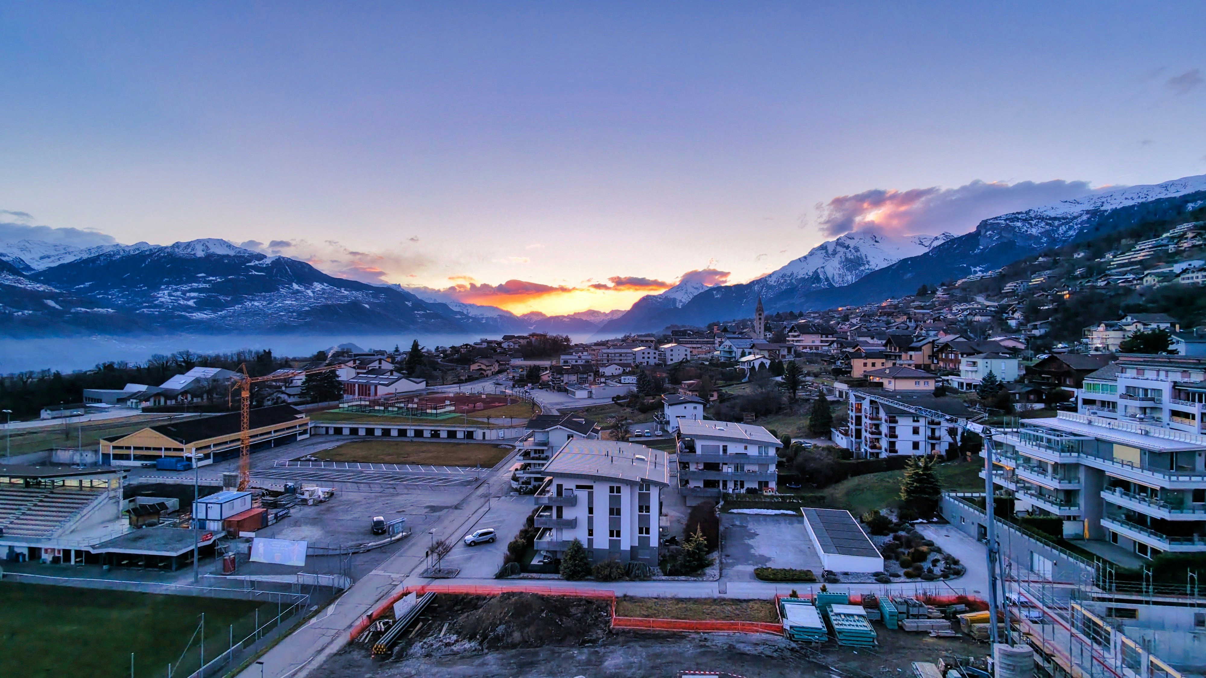 Sunrise over a mountain town with snow-capped peaks.