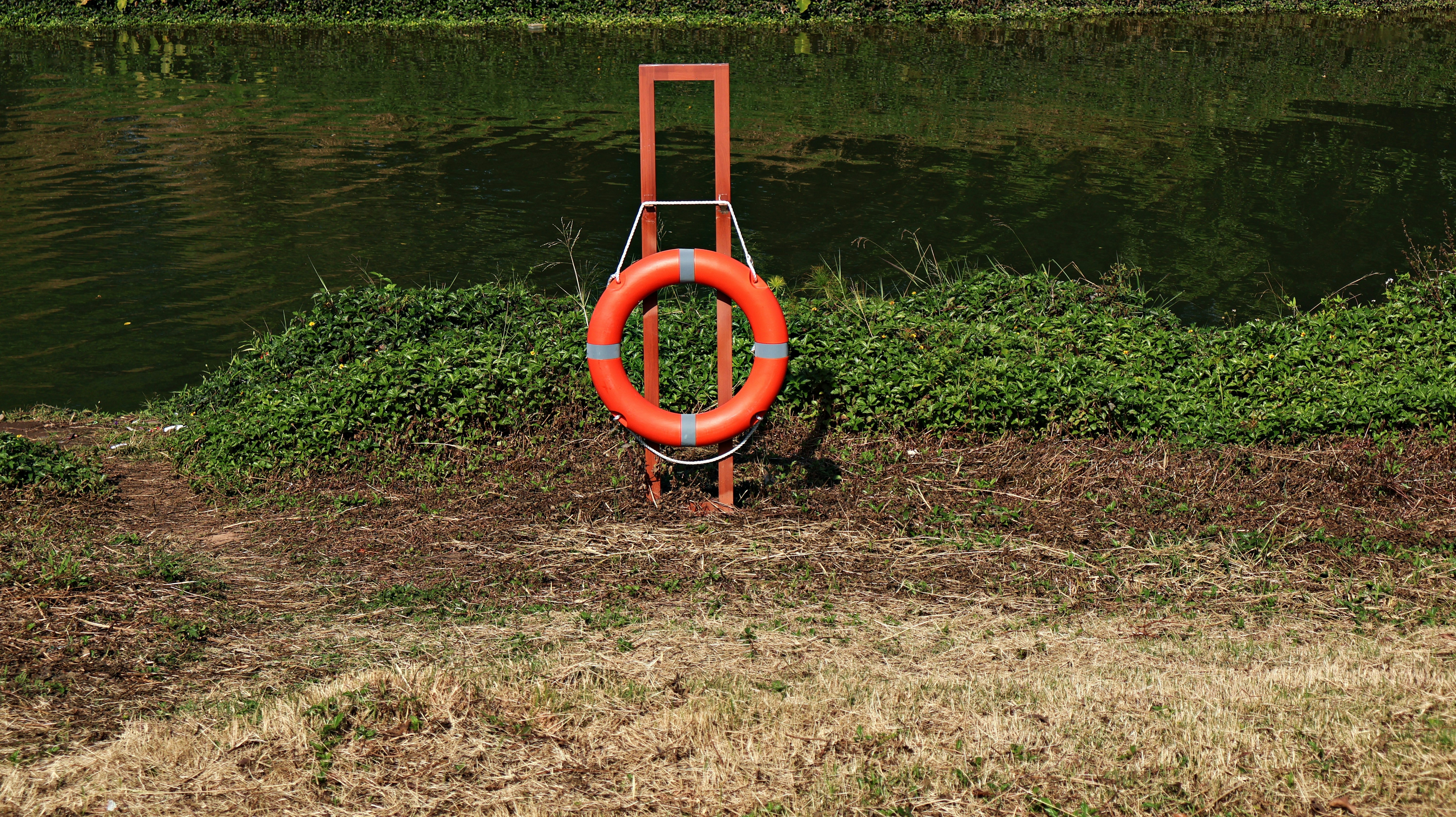 Orange life preserver on a stand by the water.