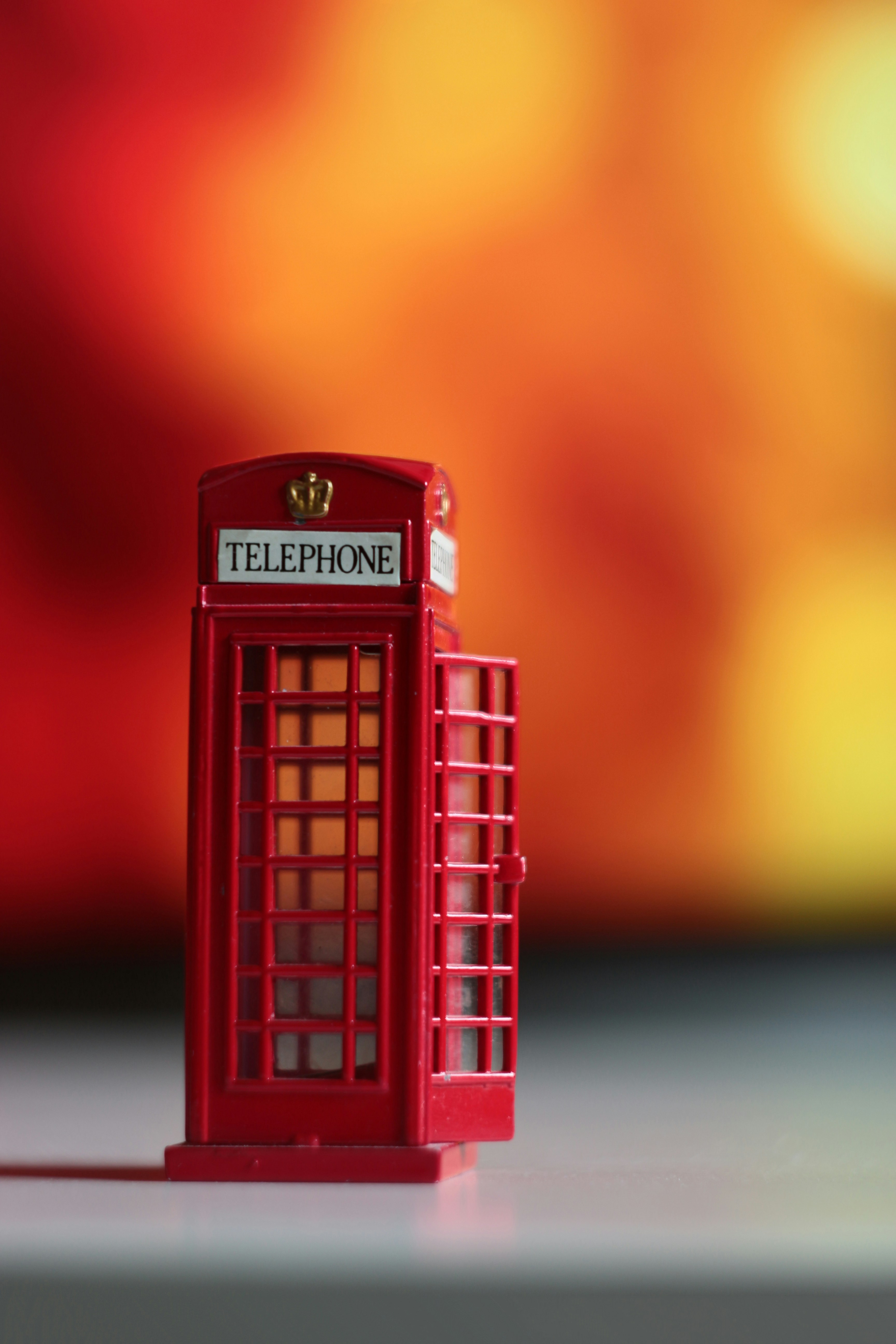A miniature red telephone booth with an open door.