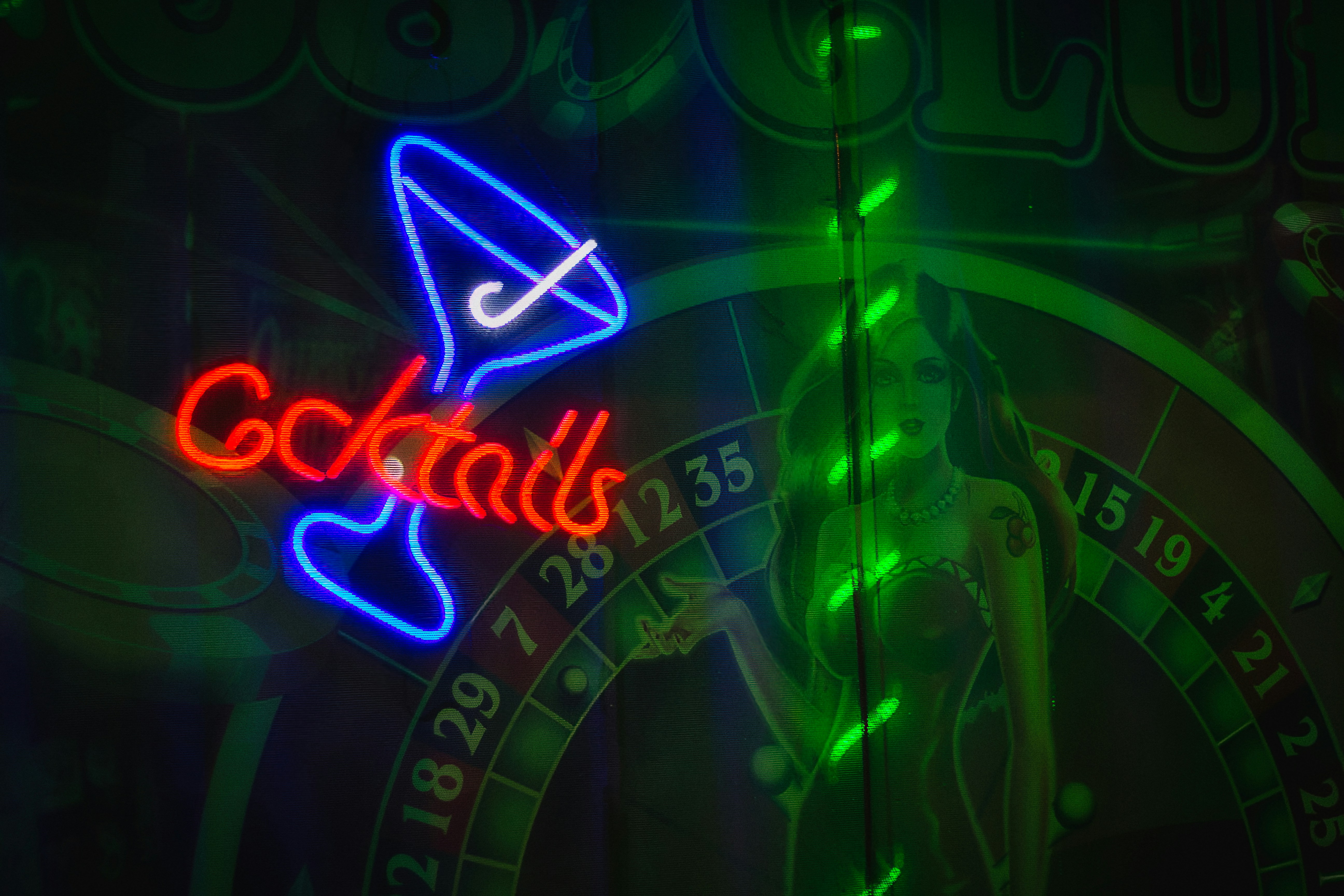 Neon cocktails sign above a roulette wheel