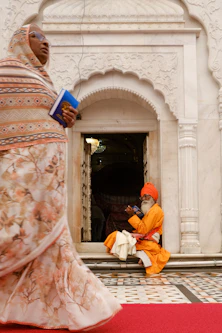 Man in orange robes sits by temple entrance