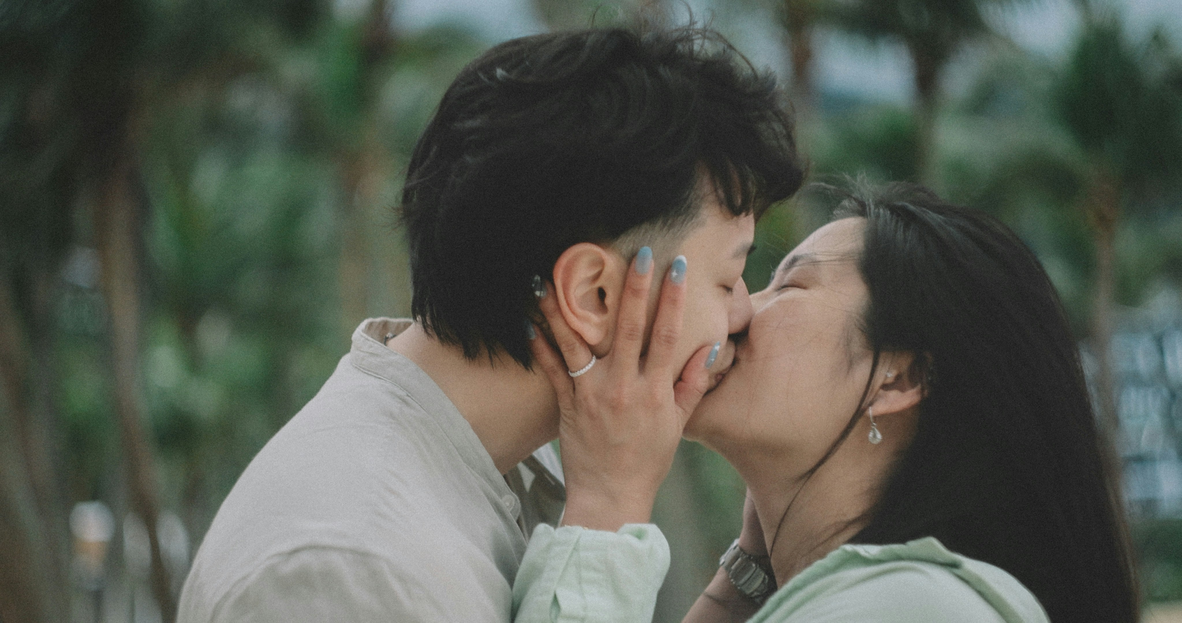 A couple shares a tender kiss outdoors.