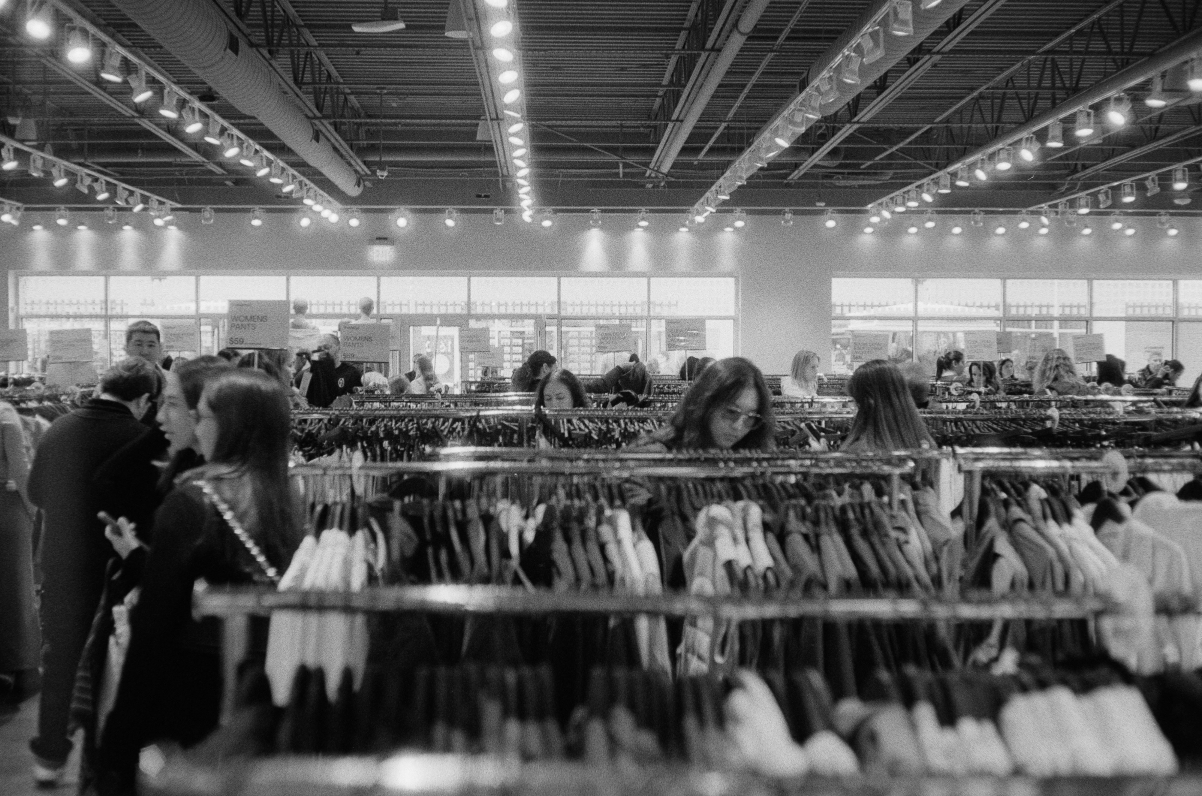 People browsing clothing racks in a well-lit store.