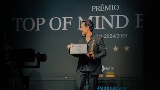 Man holding award on stage with "top of mind" sign