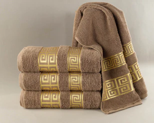 Stack of brown towels with gold greek key pattern