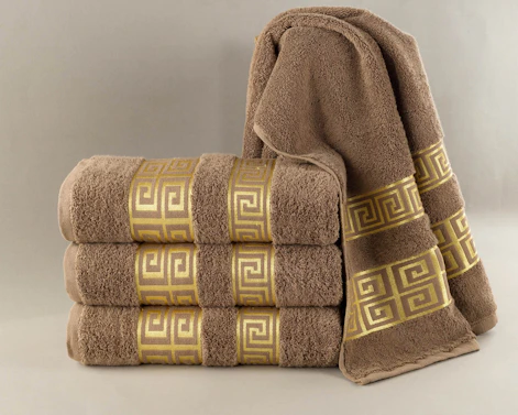 Stack of brown towels with gold greek key pattern