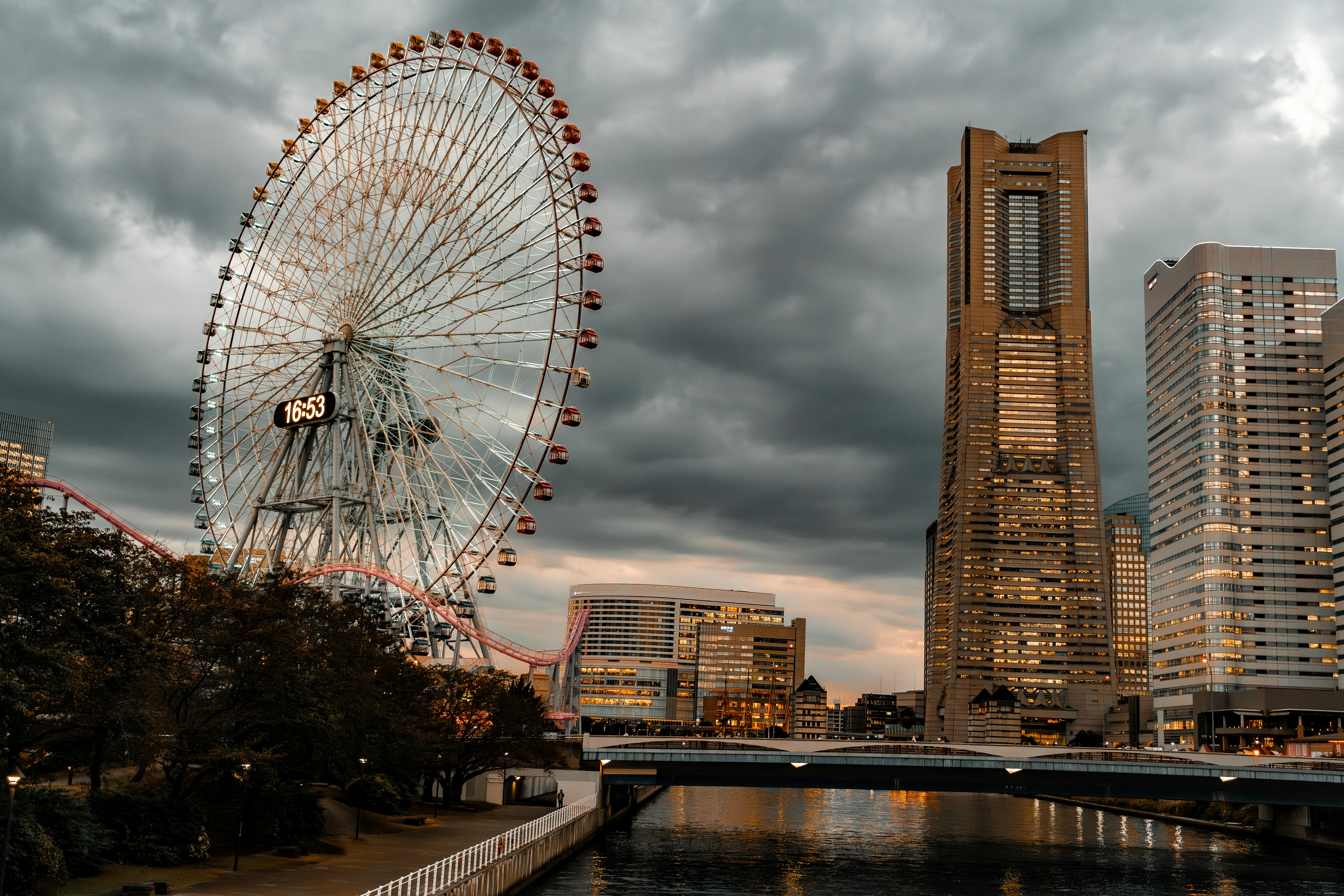 Ferris wheel and skyscraper under cloudy sky