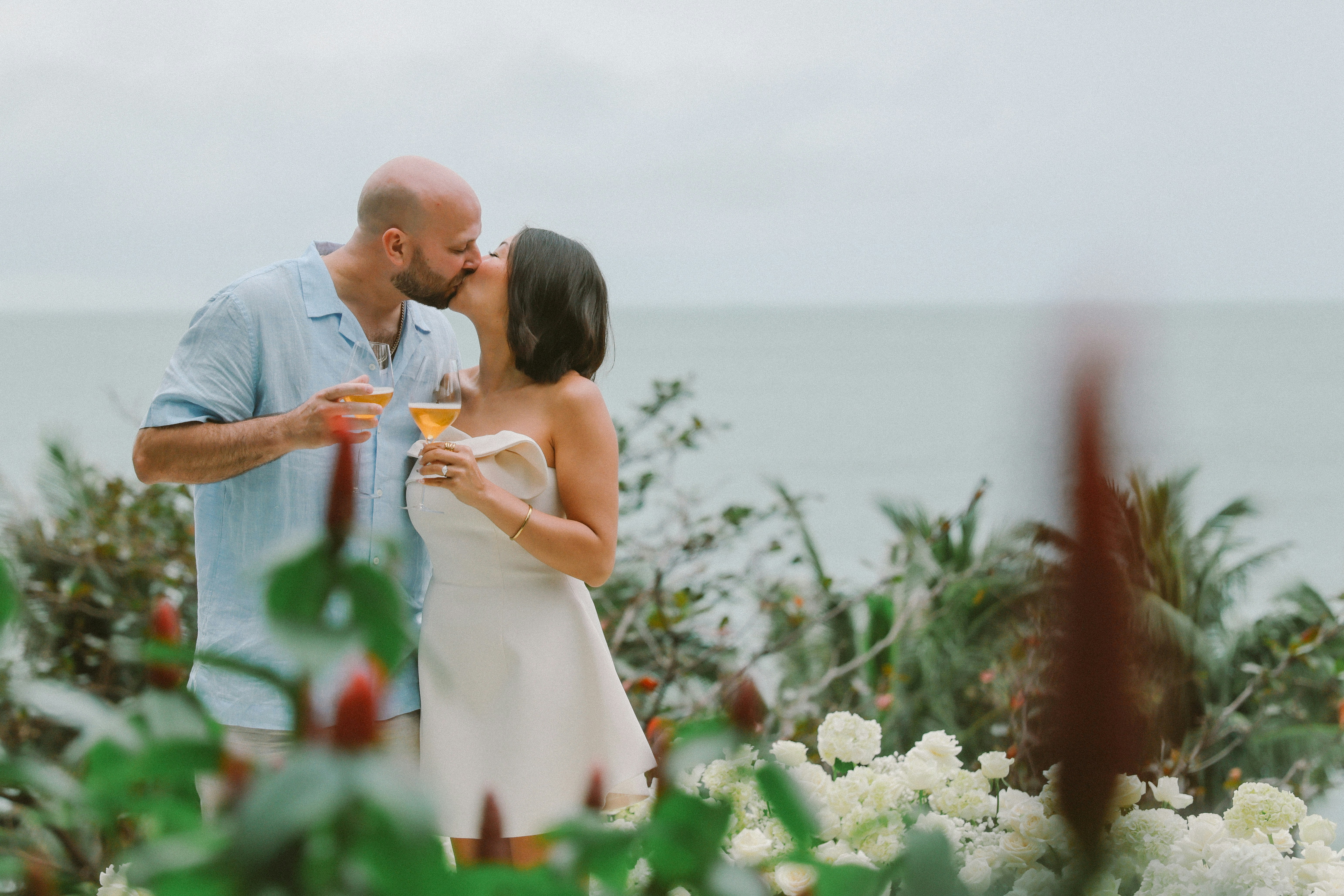 Couple kissing by the ocean with drinks