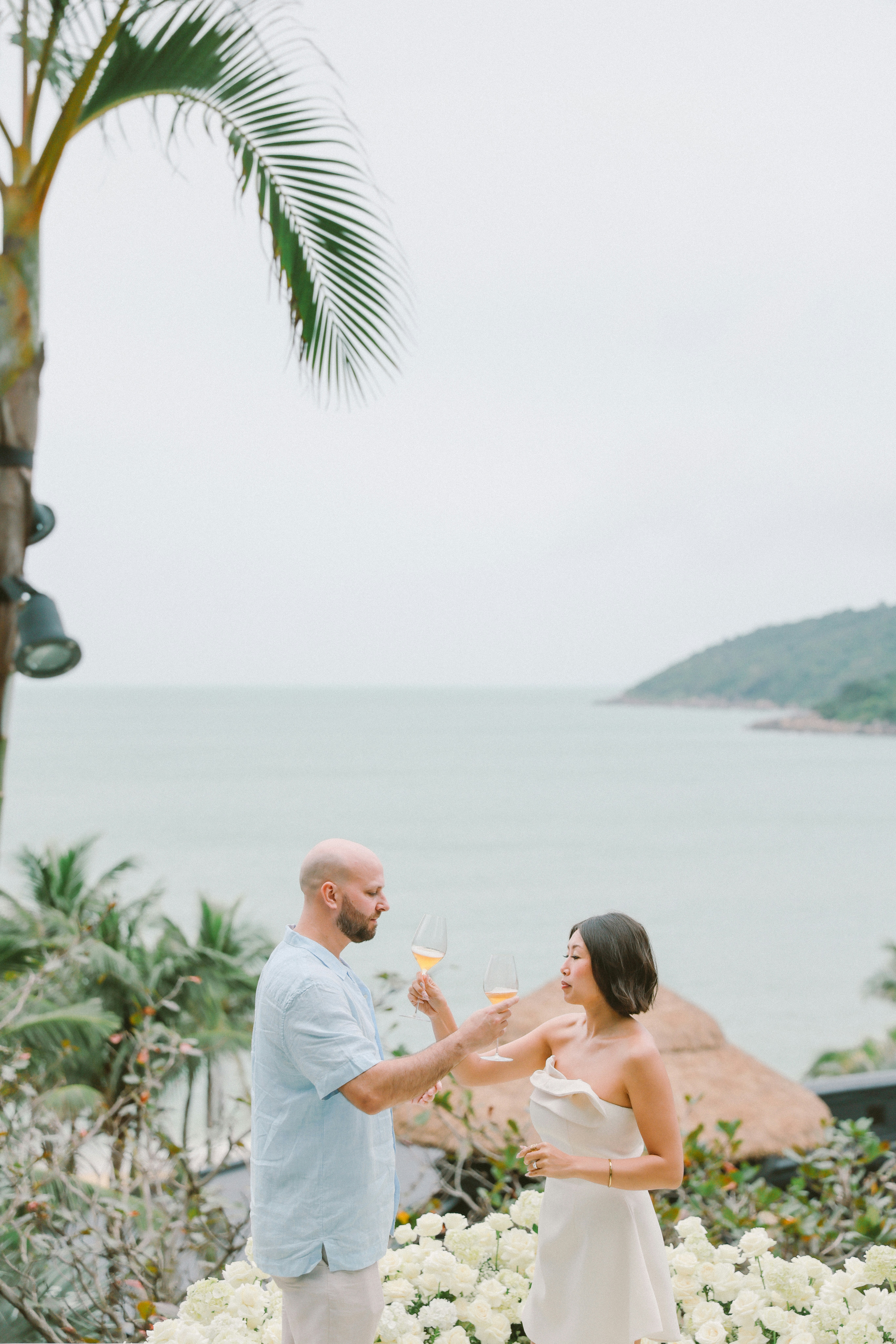 Couple toasting with drinks by the ocean