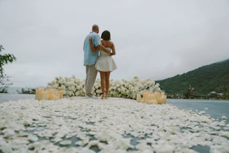 Couple embracing on a path of flower petals.