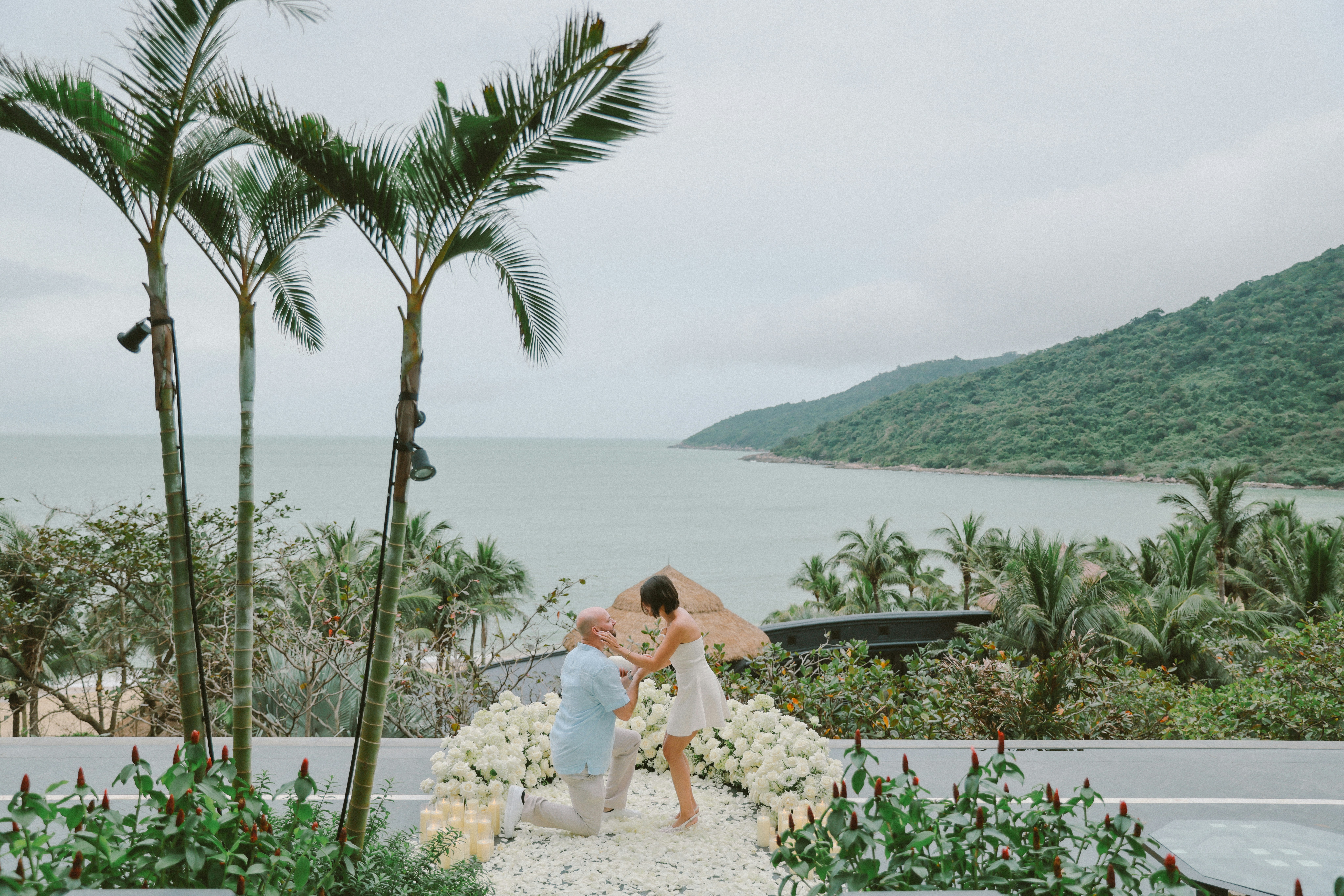 Man proposes to woman on a scenic coastal overlook.