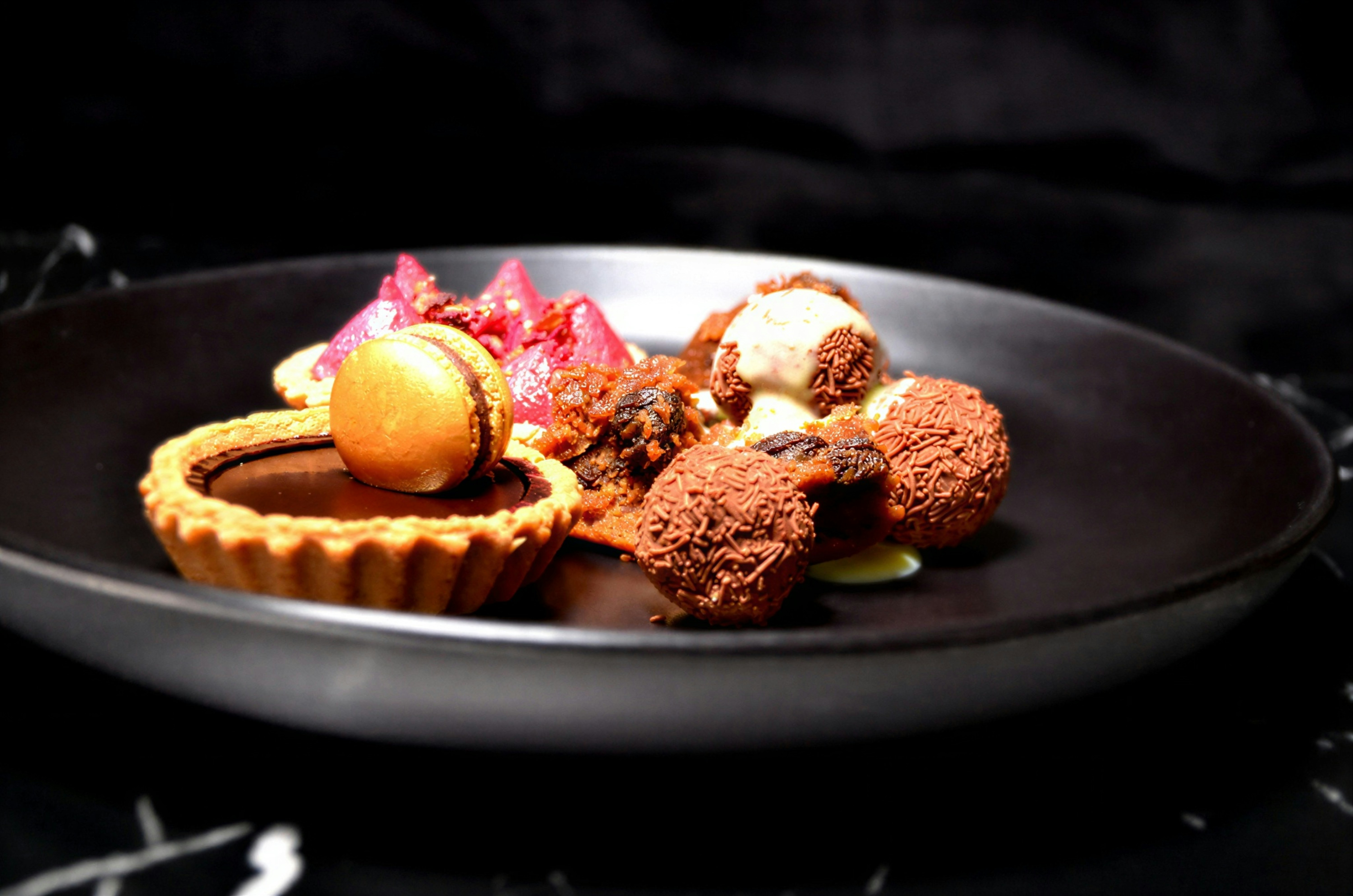 Assortment of gourmet chocolates and tart on plate