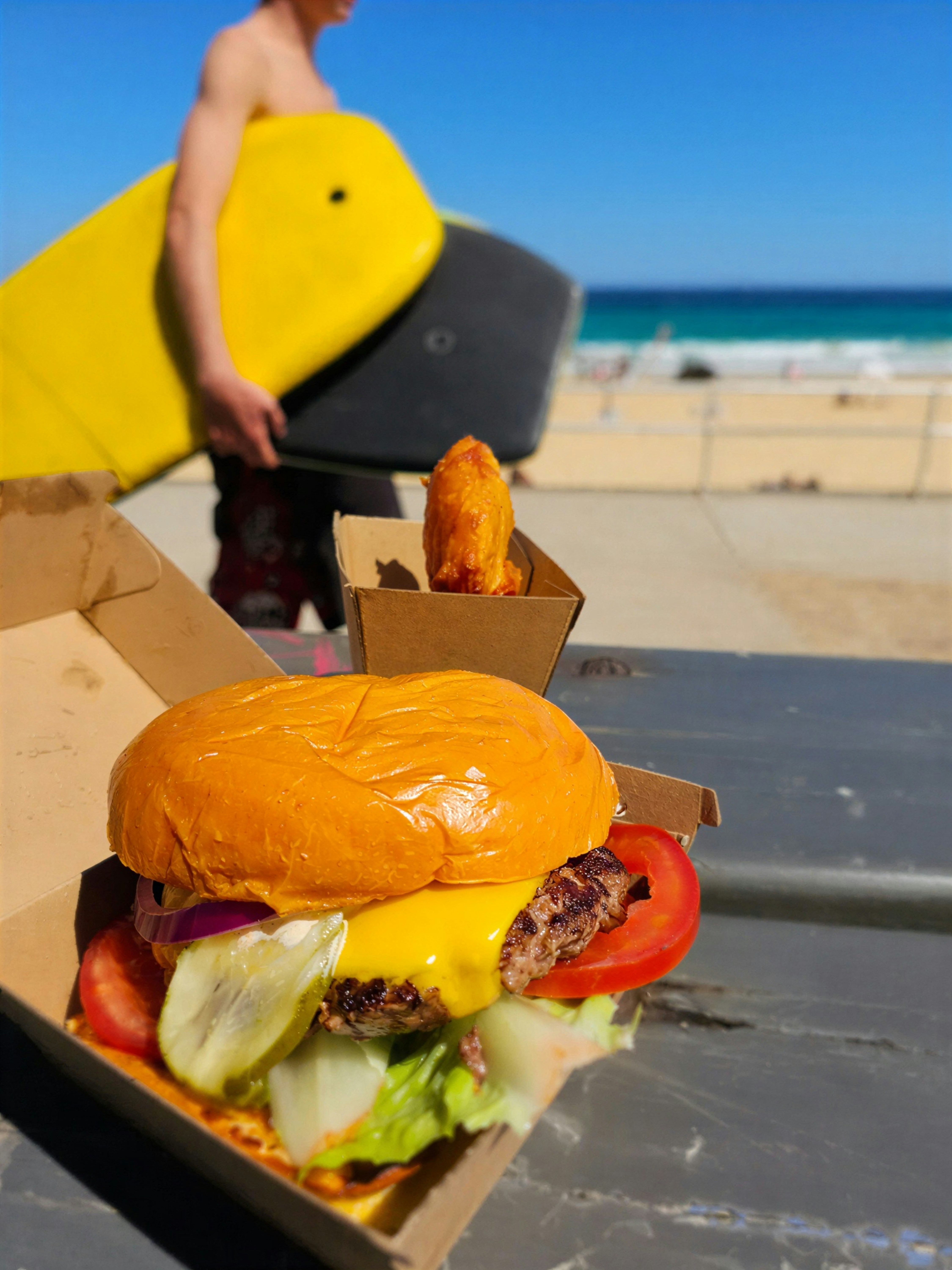 Burger and fries at the beach with surfboard