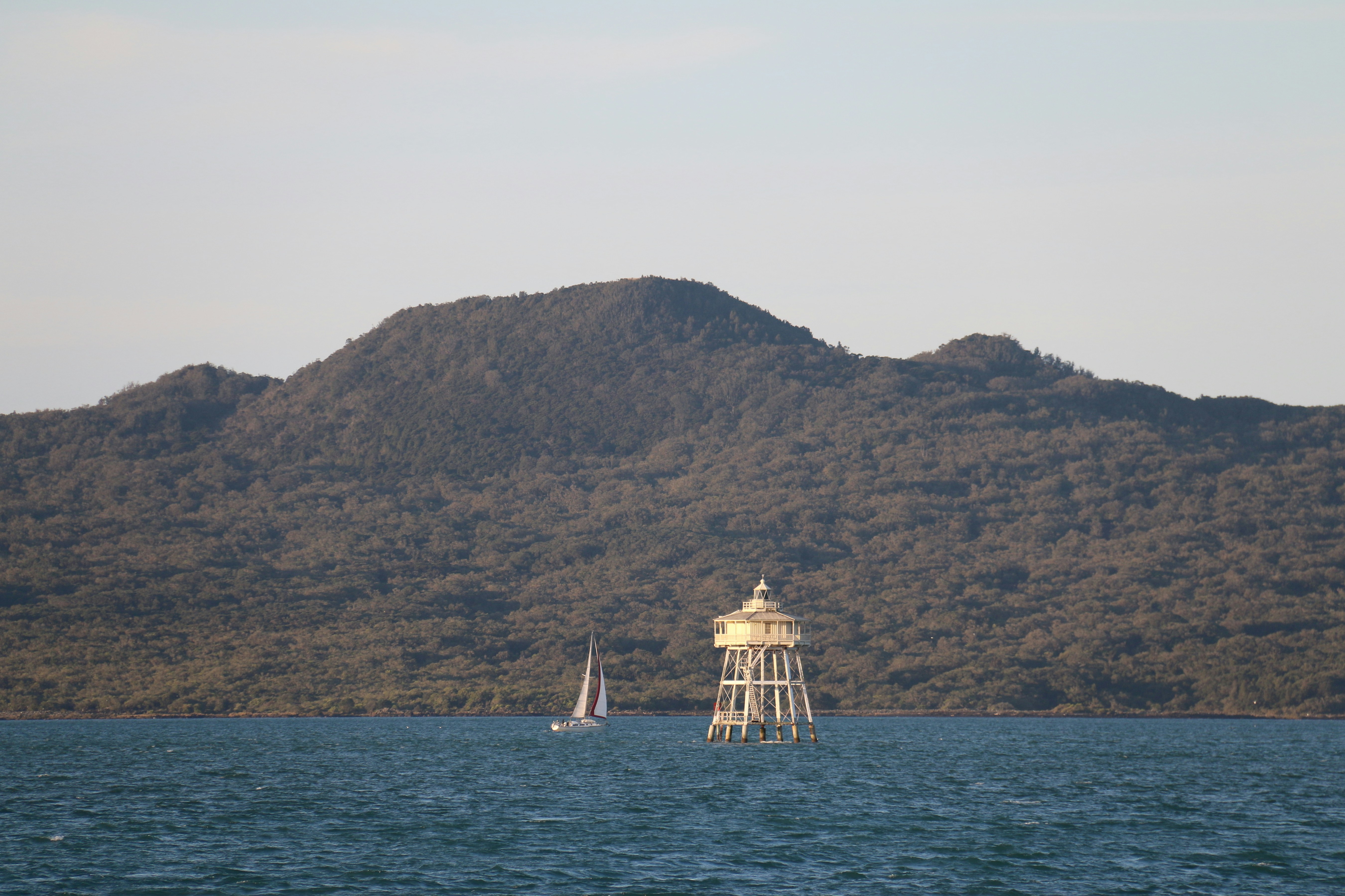Un voilier et un phare sur l’eau