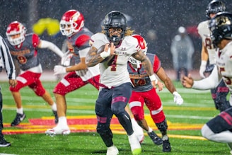 Football player running with ball during rainy game.