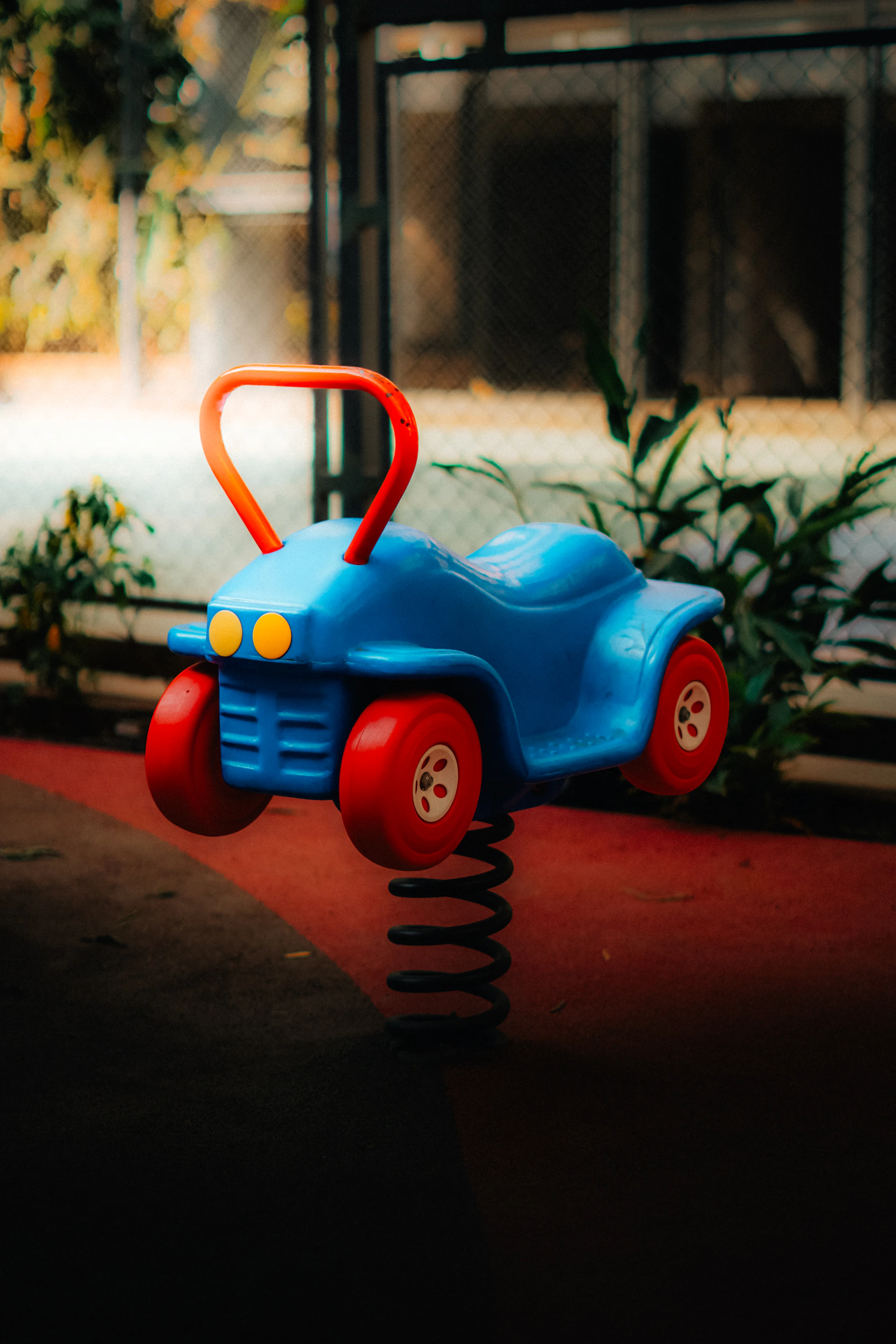 A blue toy car with red wheels on a spring