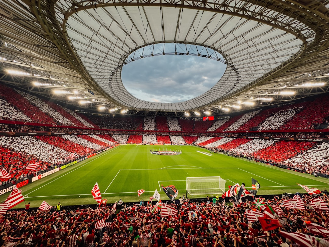 A packed stadium with red and white supporters cheering fans.