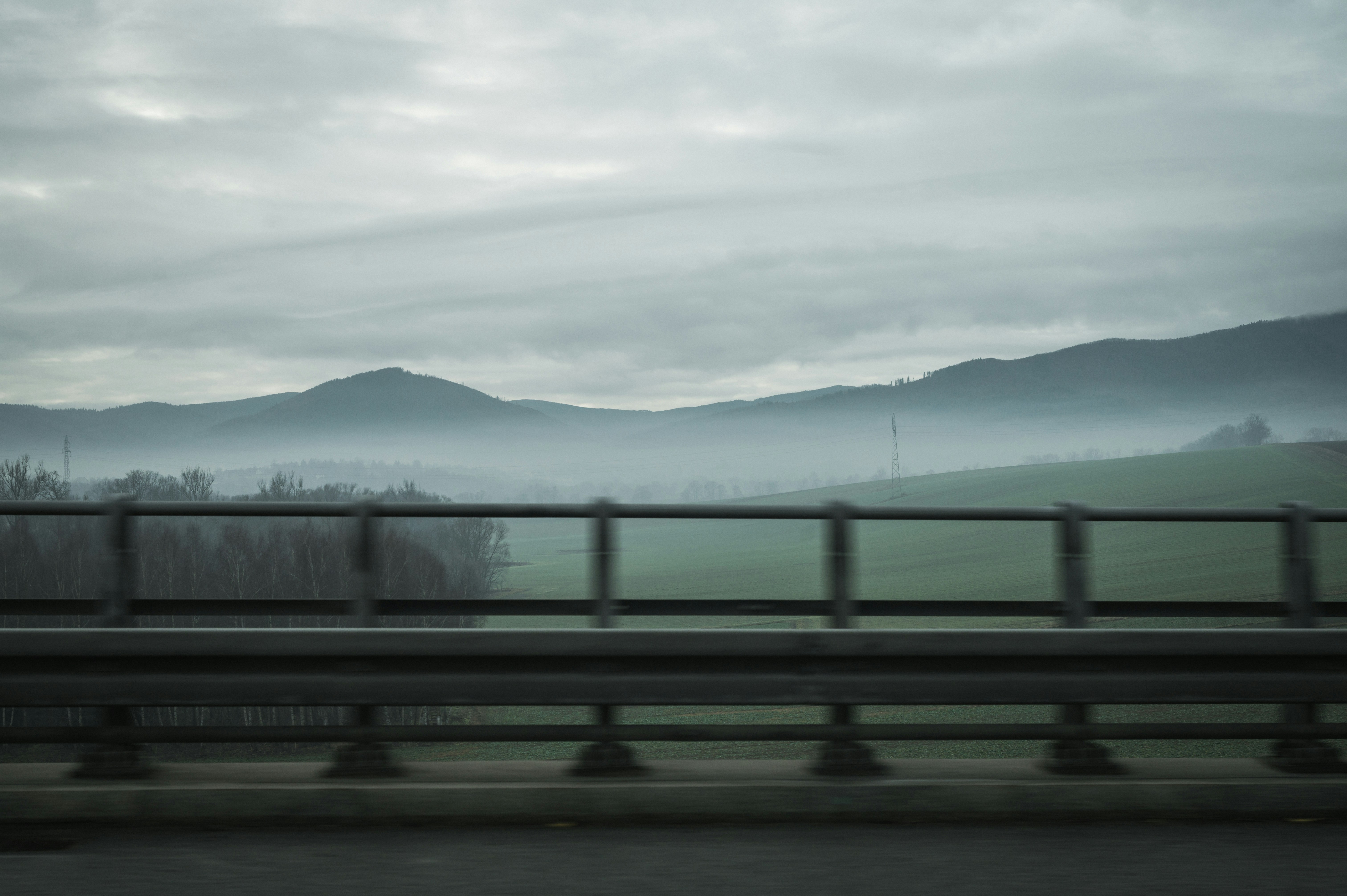Misty mountains and green fields viewed from a bridge