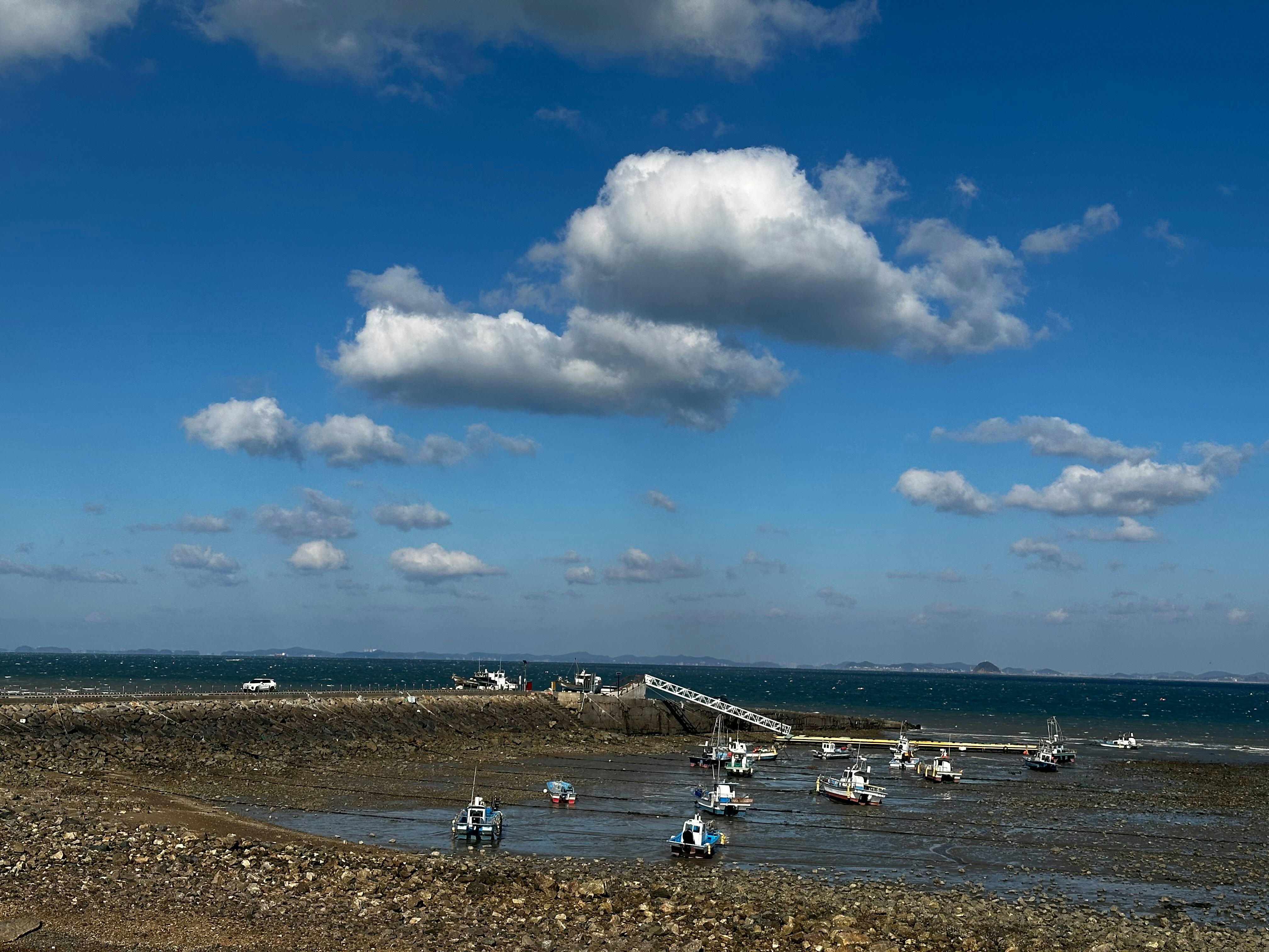 Small boats resting on a rocky shore under blue sky.