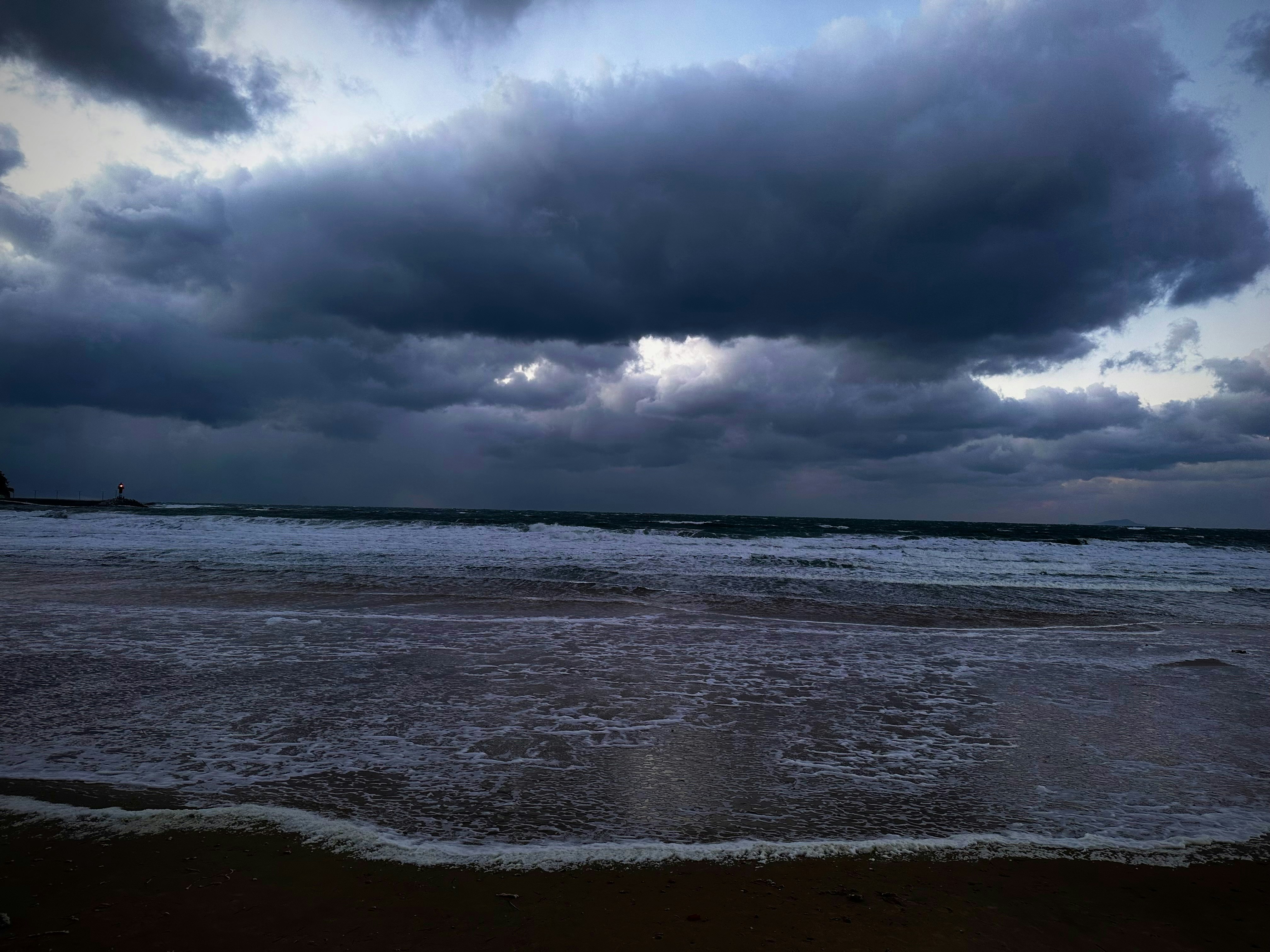 Dark stormy clouds over a rough ocean and beach.