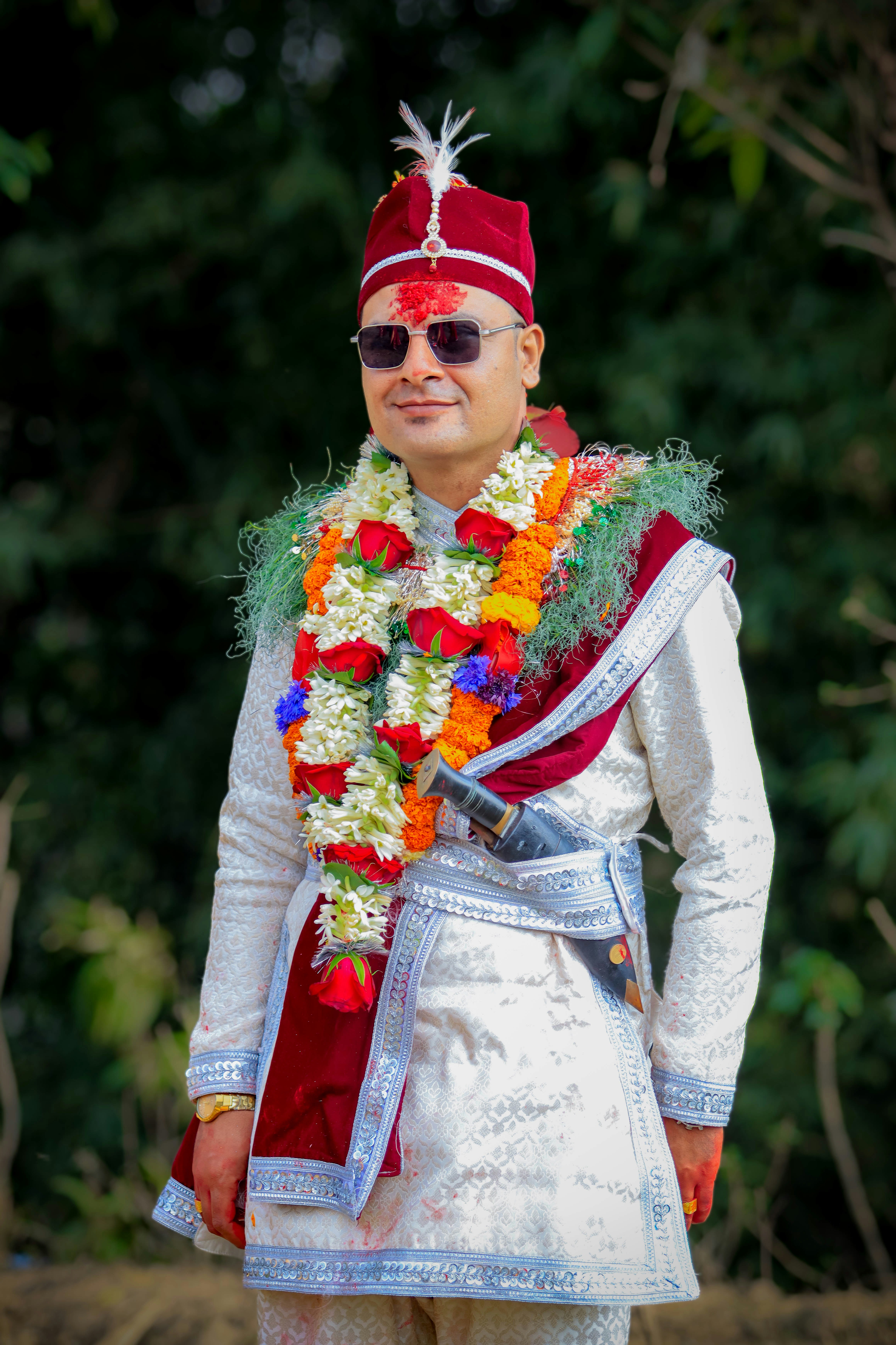 Man in traditional wedding attire with floral garlands.