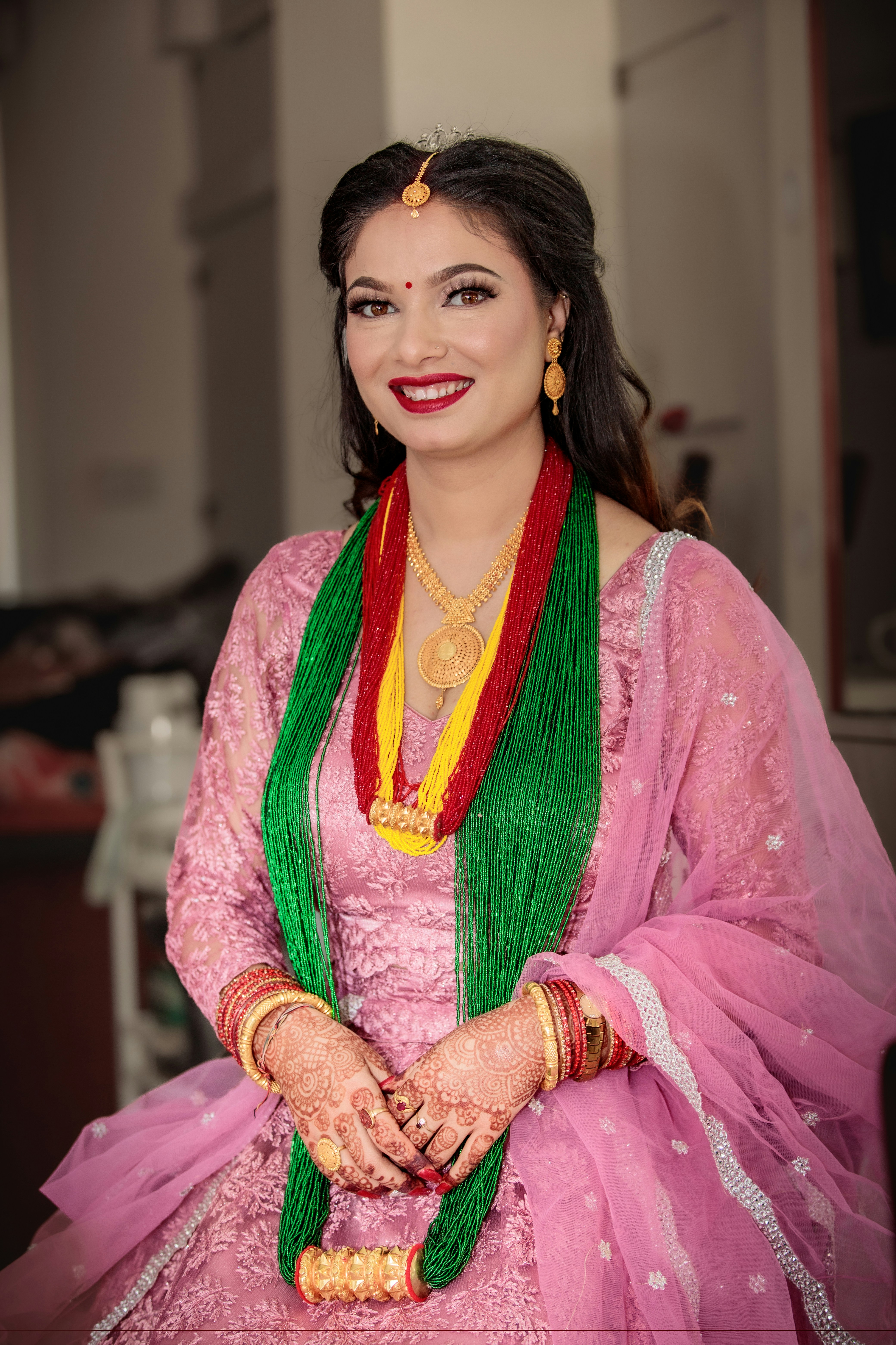 A smiling woman in traditional pink attire and jewelry.