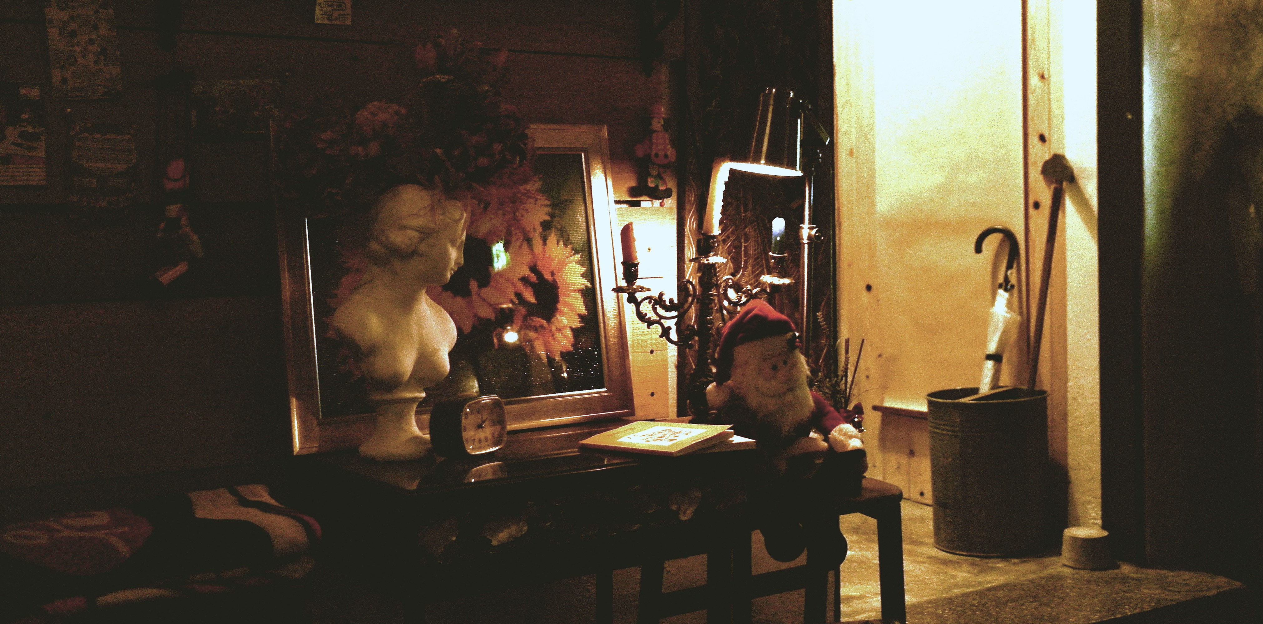 Busto y flores sobre una mesa en una habitación tenuemente iluminada.