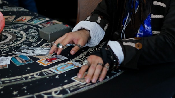 Hands arranging tarot cards on a celestial patterned cloth.