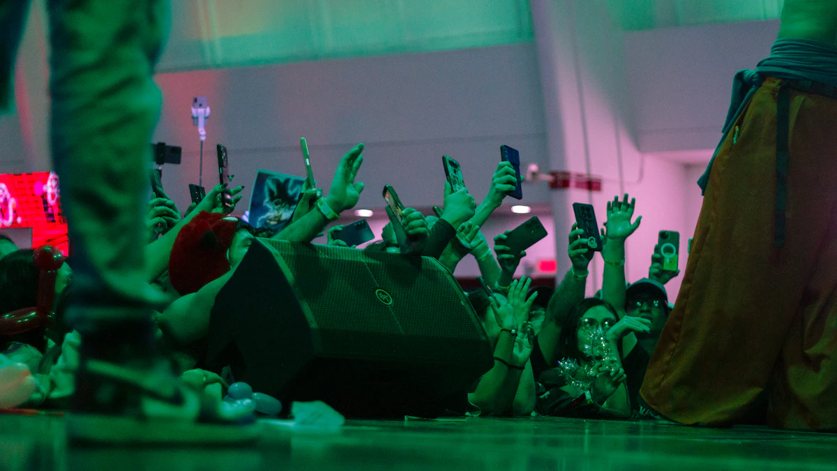 View from the stage of a fun concert crowd with phones raised, lit by teal and red stage lights