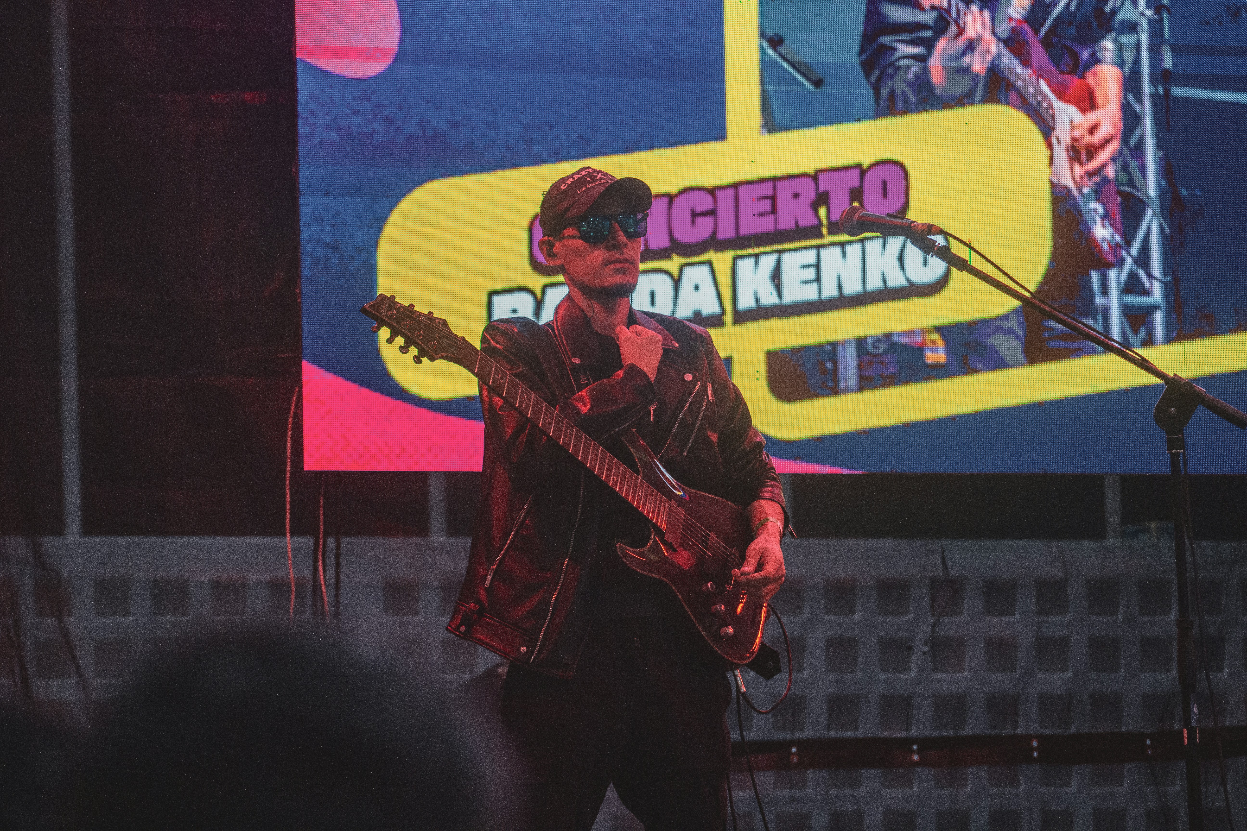 Musician playing guitar on stage at concert.