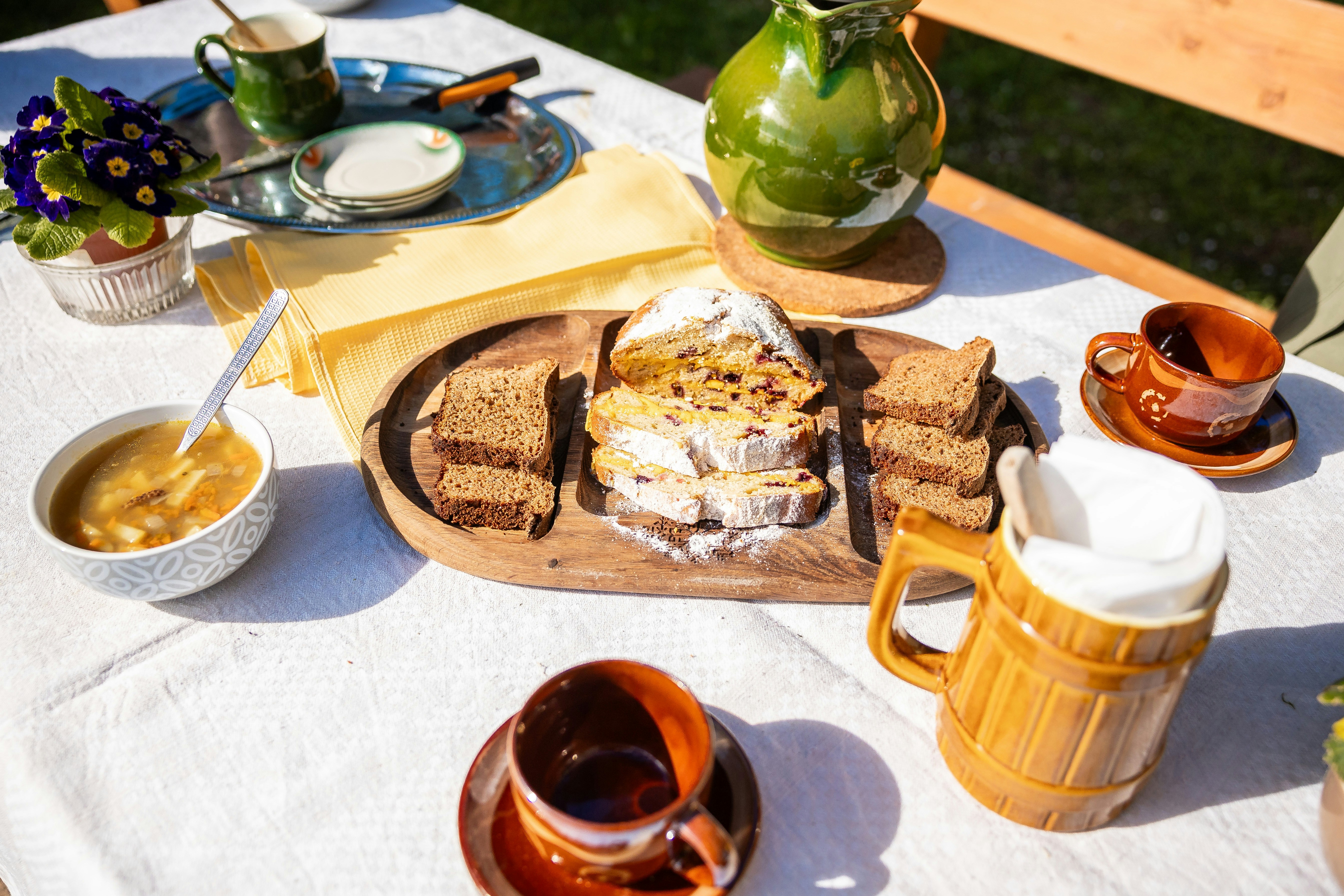 Mesa com pão, sopa e bebidas ao ar livre para café