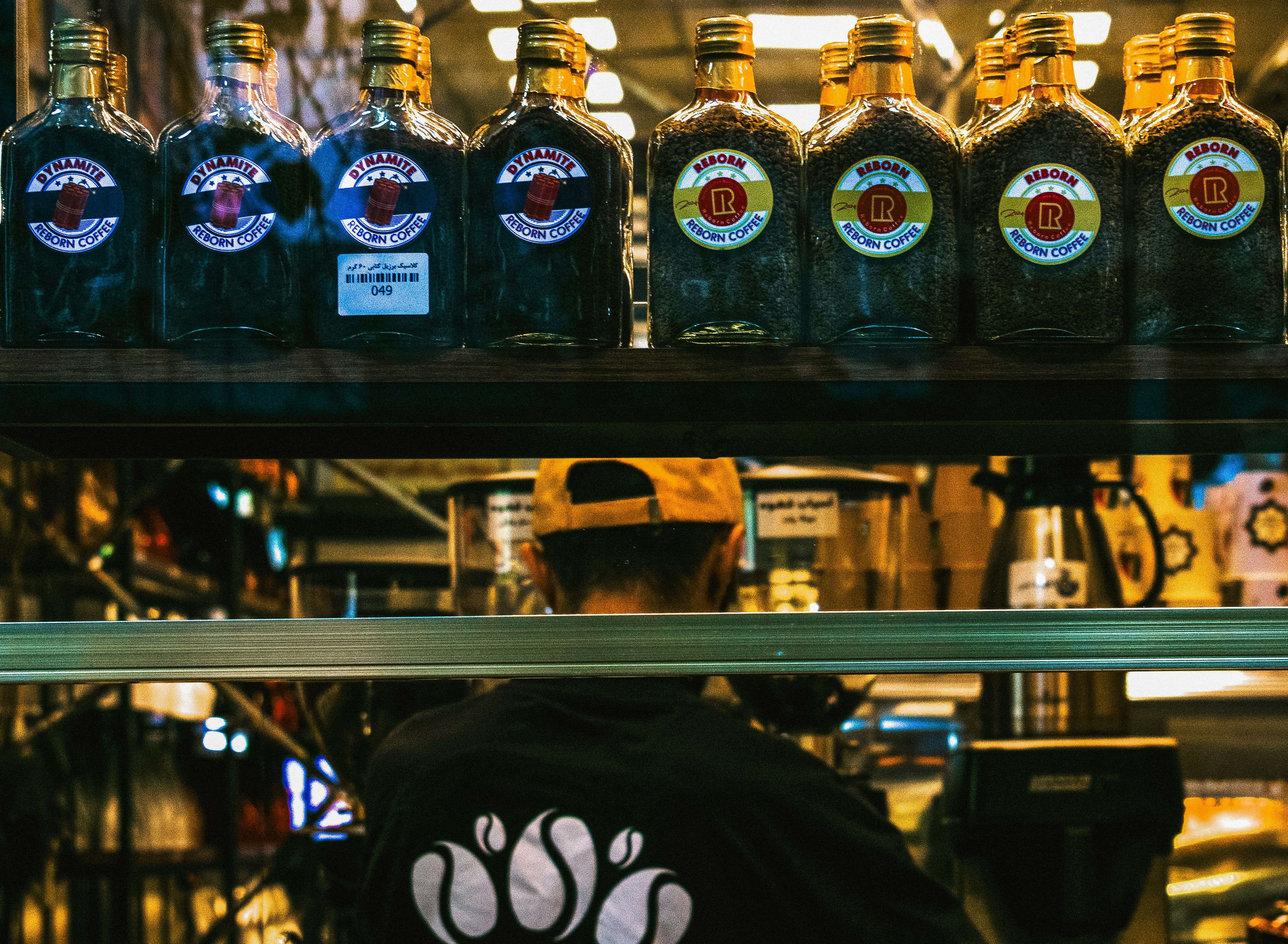 Des bouteilles alignées sur une étagère au-dessus d’une personne.