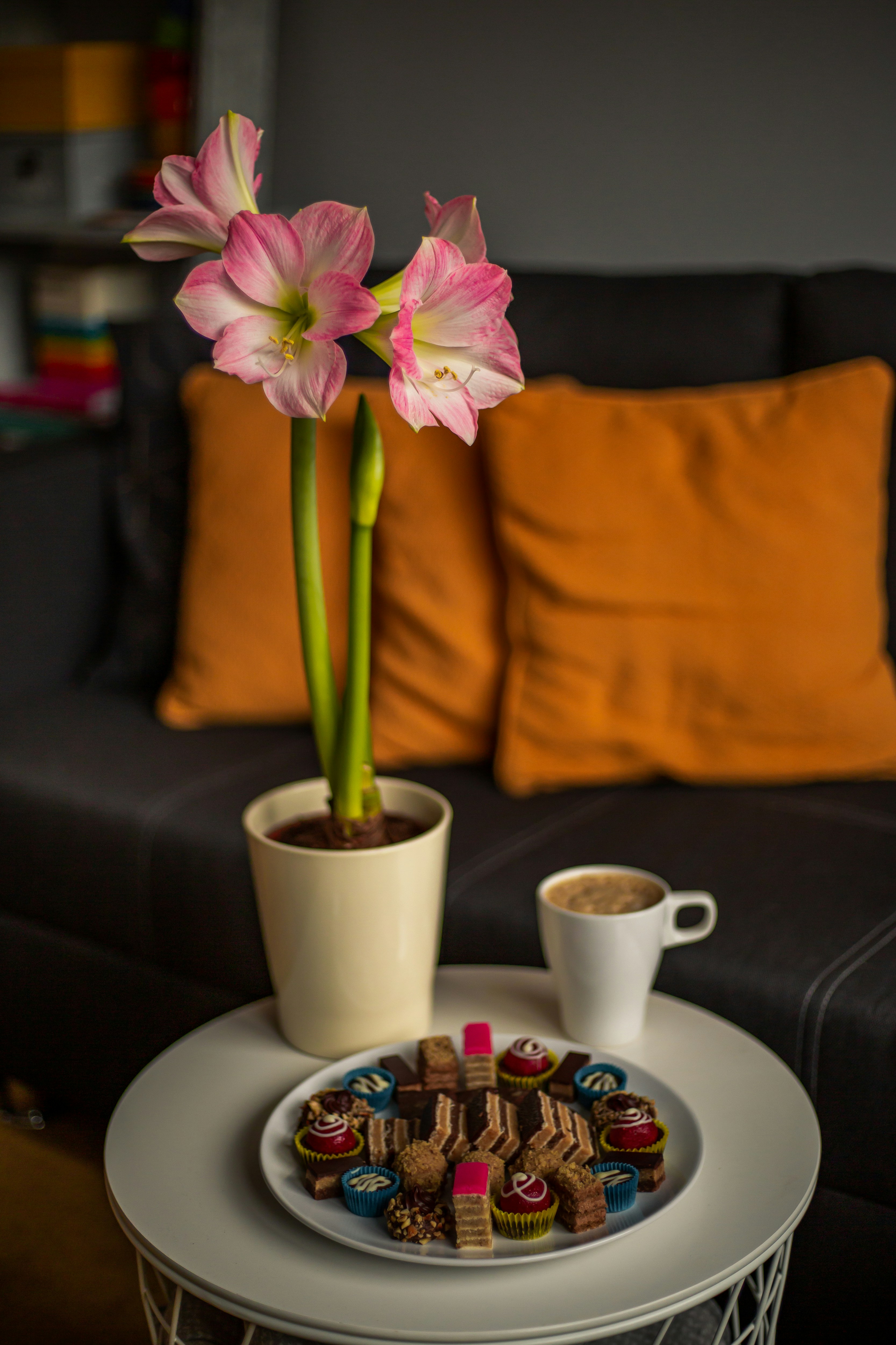 Pink flowers with chocolates and coffee on table.